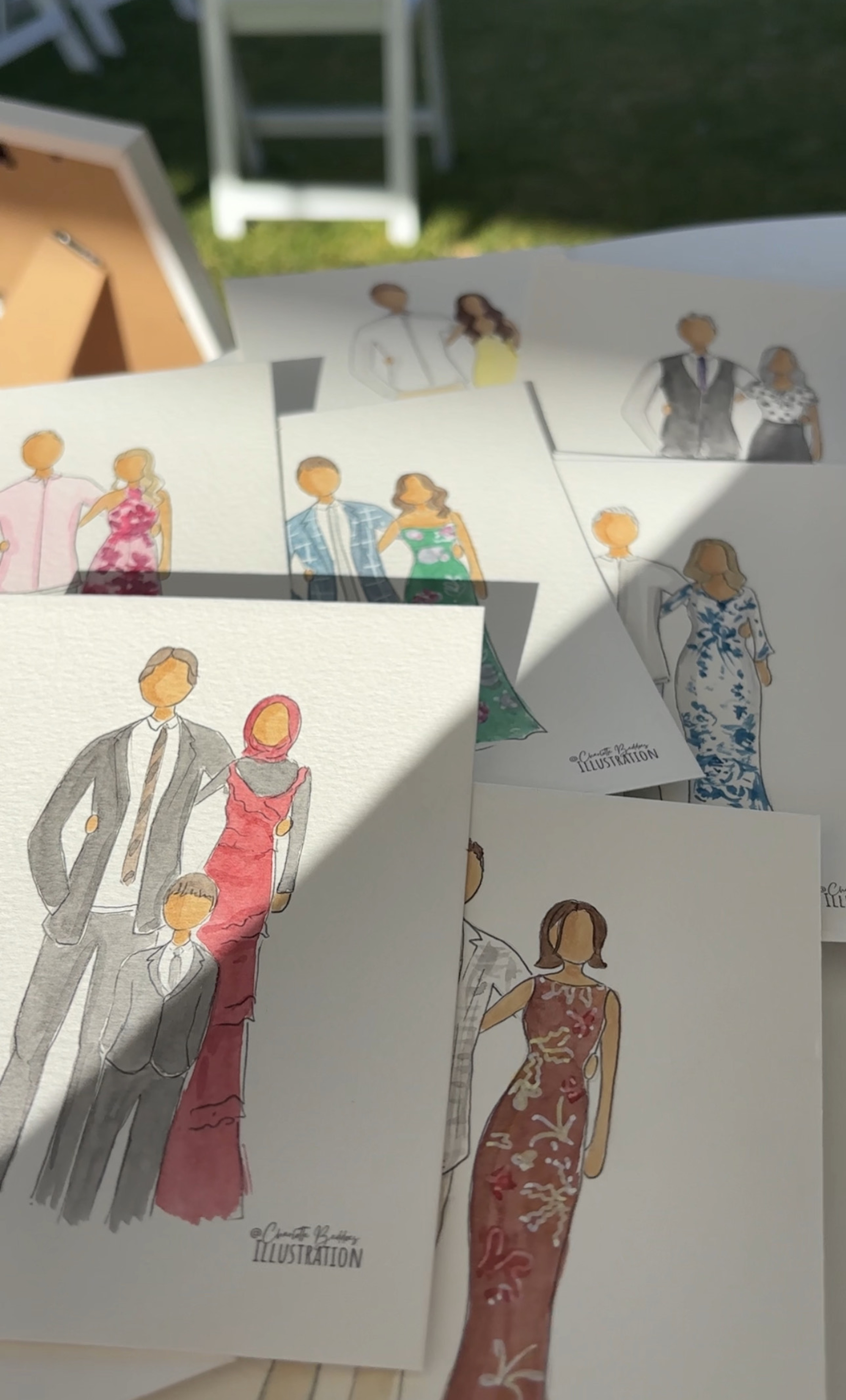 Assorted custom watercolor-style wedding guest portraits displayed on a table in natural light.