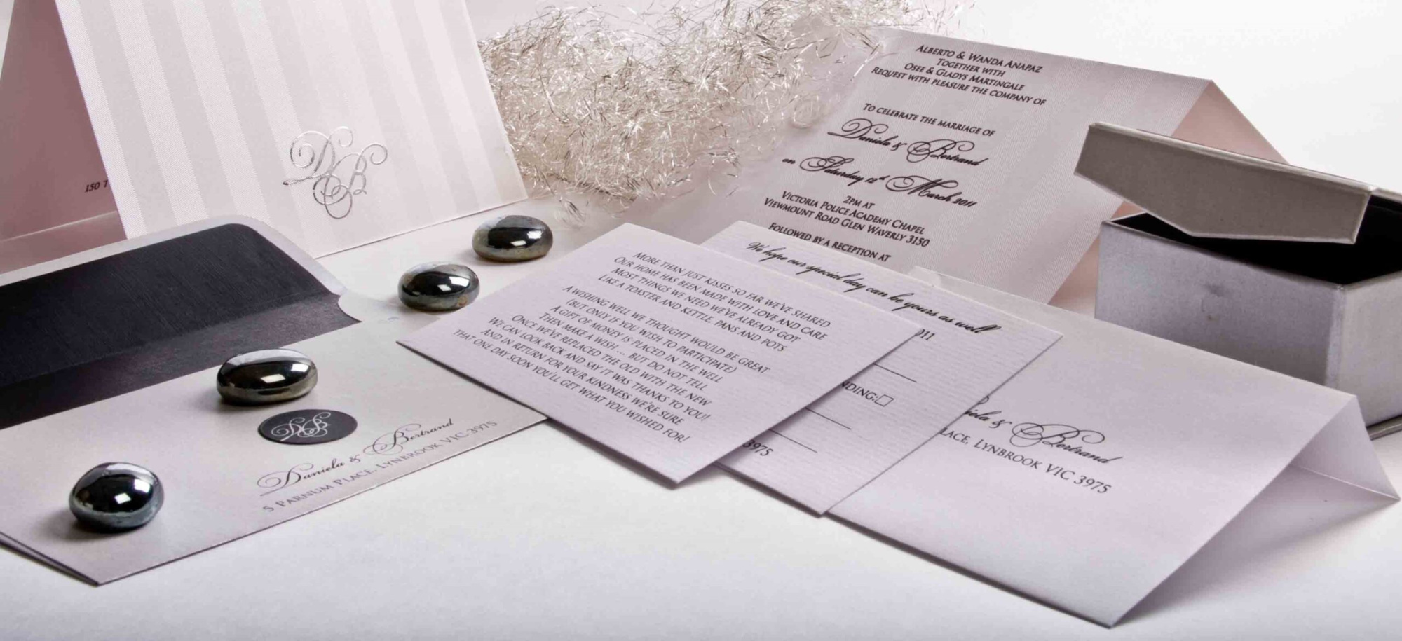 Elegant white and silver wedding invitation suite with envelopes and metallic accents arranged on a light surface.