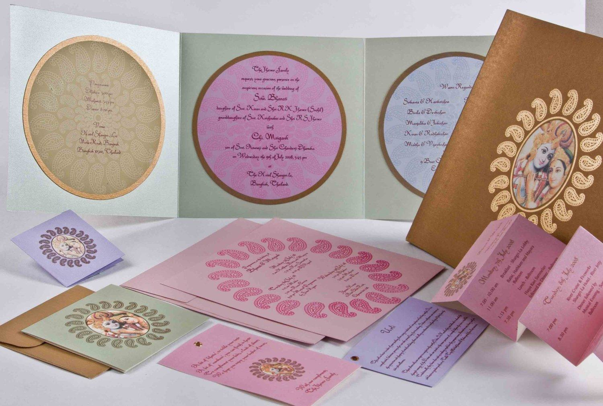 Colorful Indian wedding invitation suite with circular paisley designs and Hindu deity artwork displayed on a white surface.