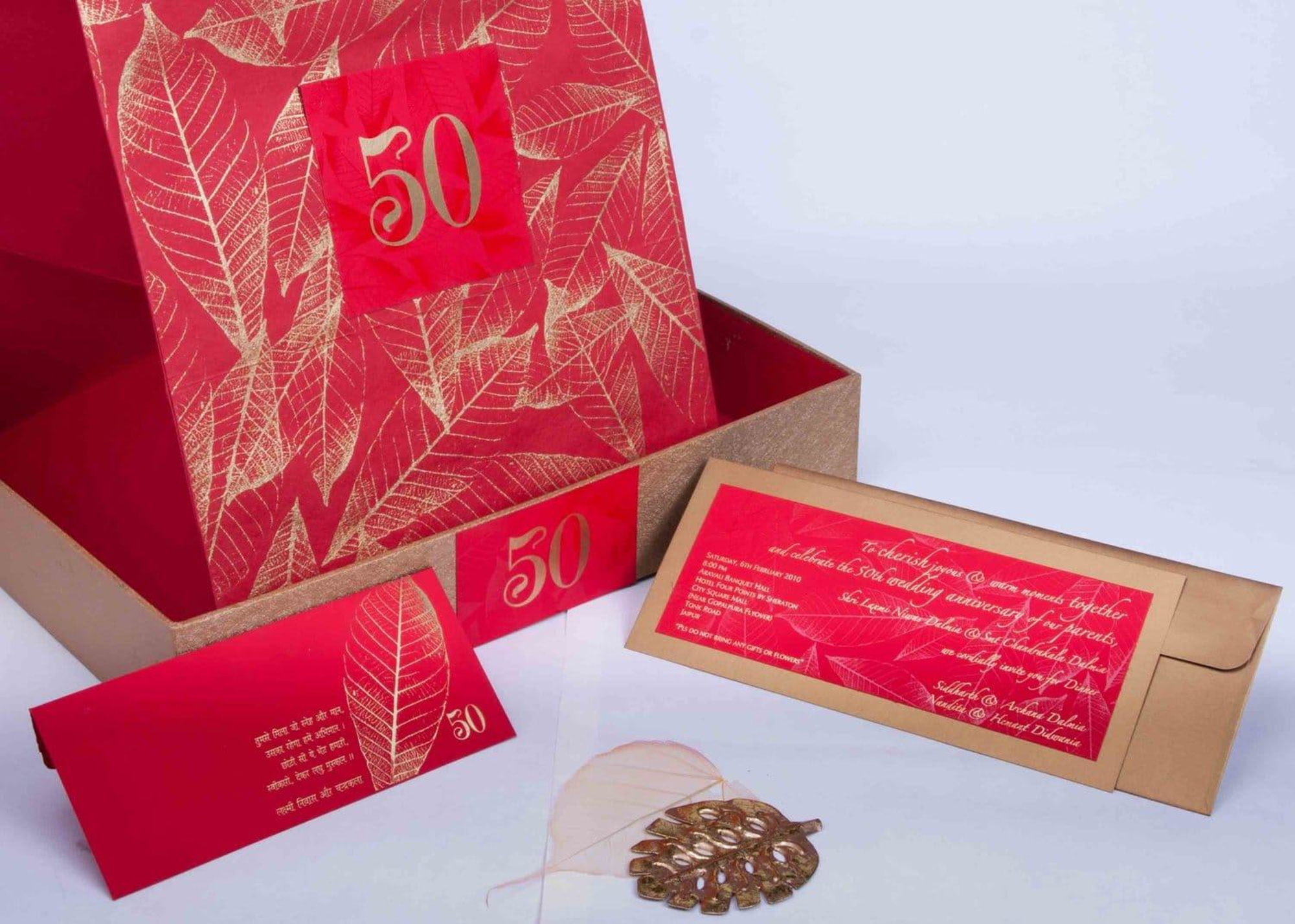 Red and gold foil-stamped boxed invitation set for a 50th wedding celebration.
