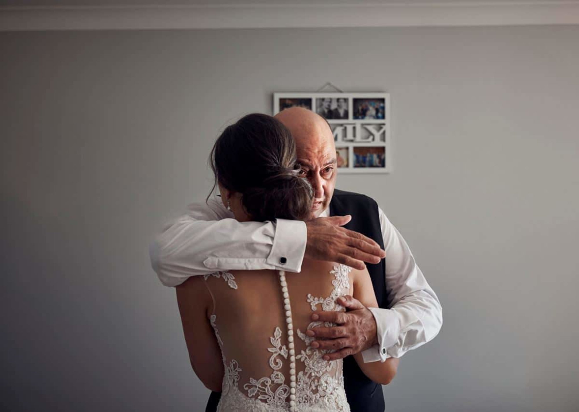 Father emotionally embracing his daughter in a lace wedding dress before the ceremony.