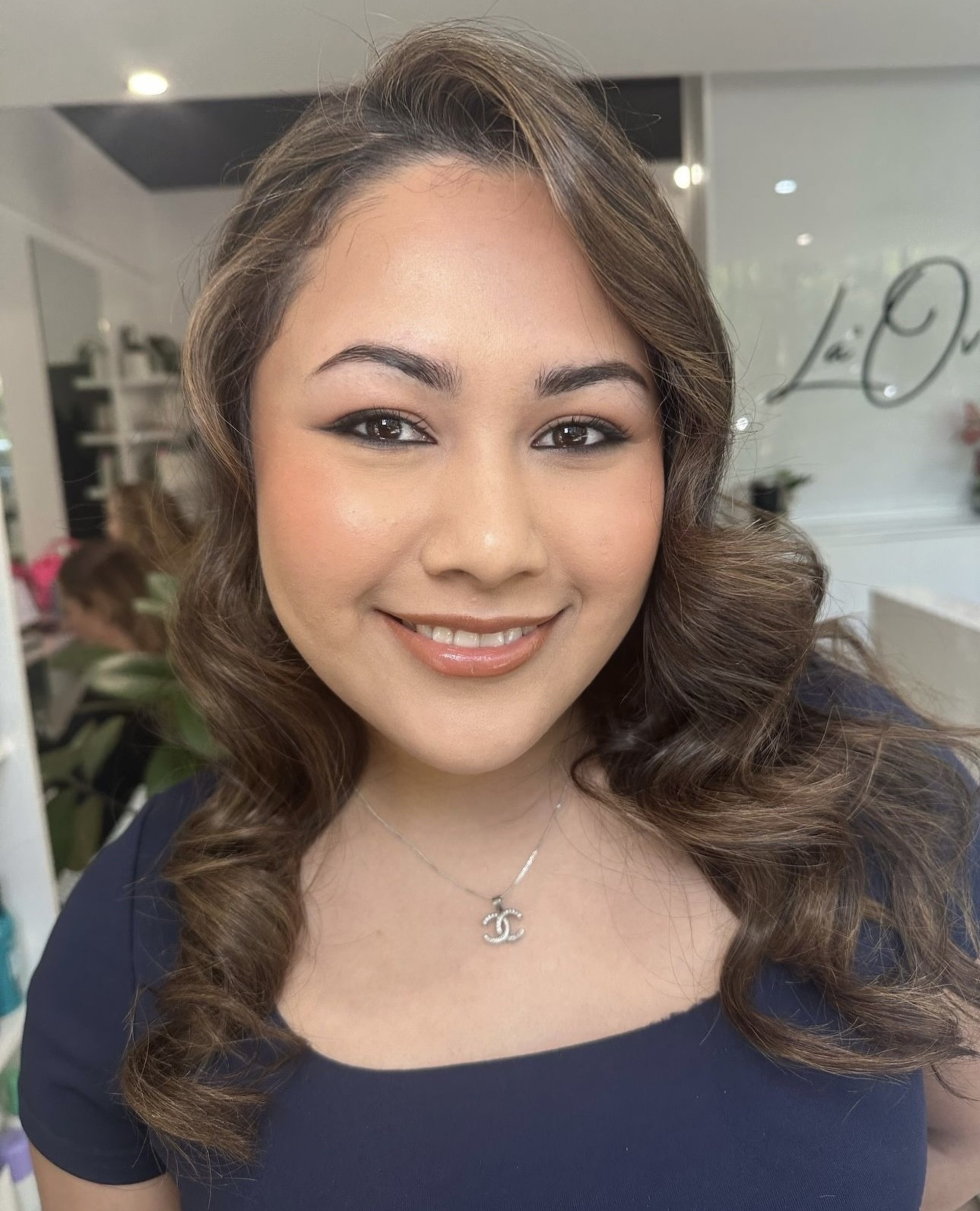 Close-up portrait of a woman with soft curls and natural glam bridal makeup in a beauty studio.