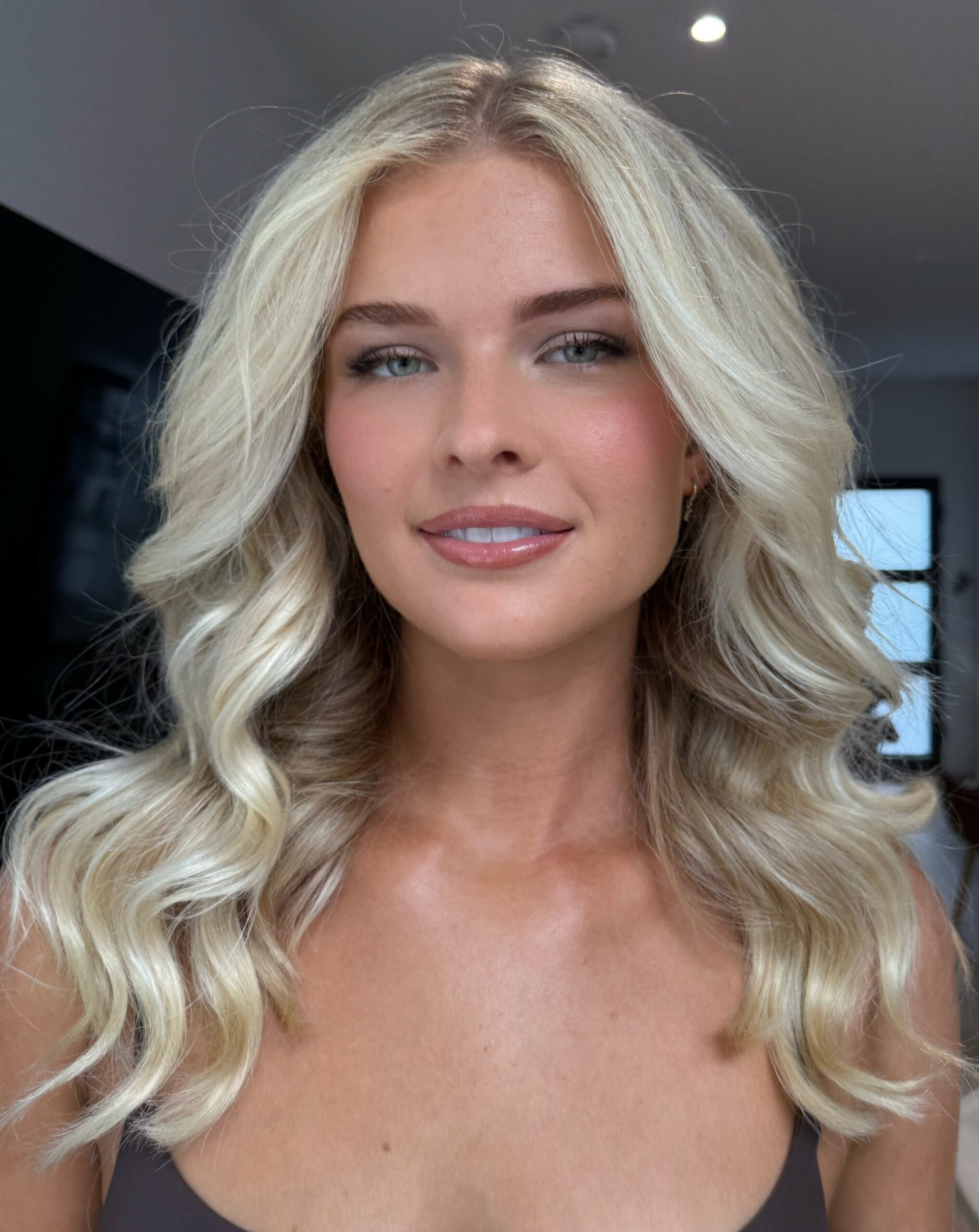 Close-up bridal beauty portrait with soft waves and natural glam makeup in indoor light.