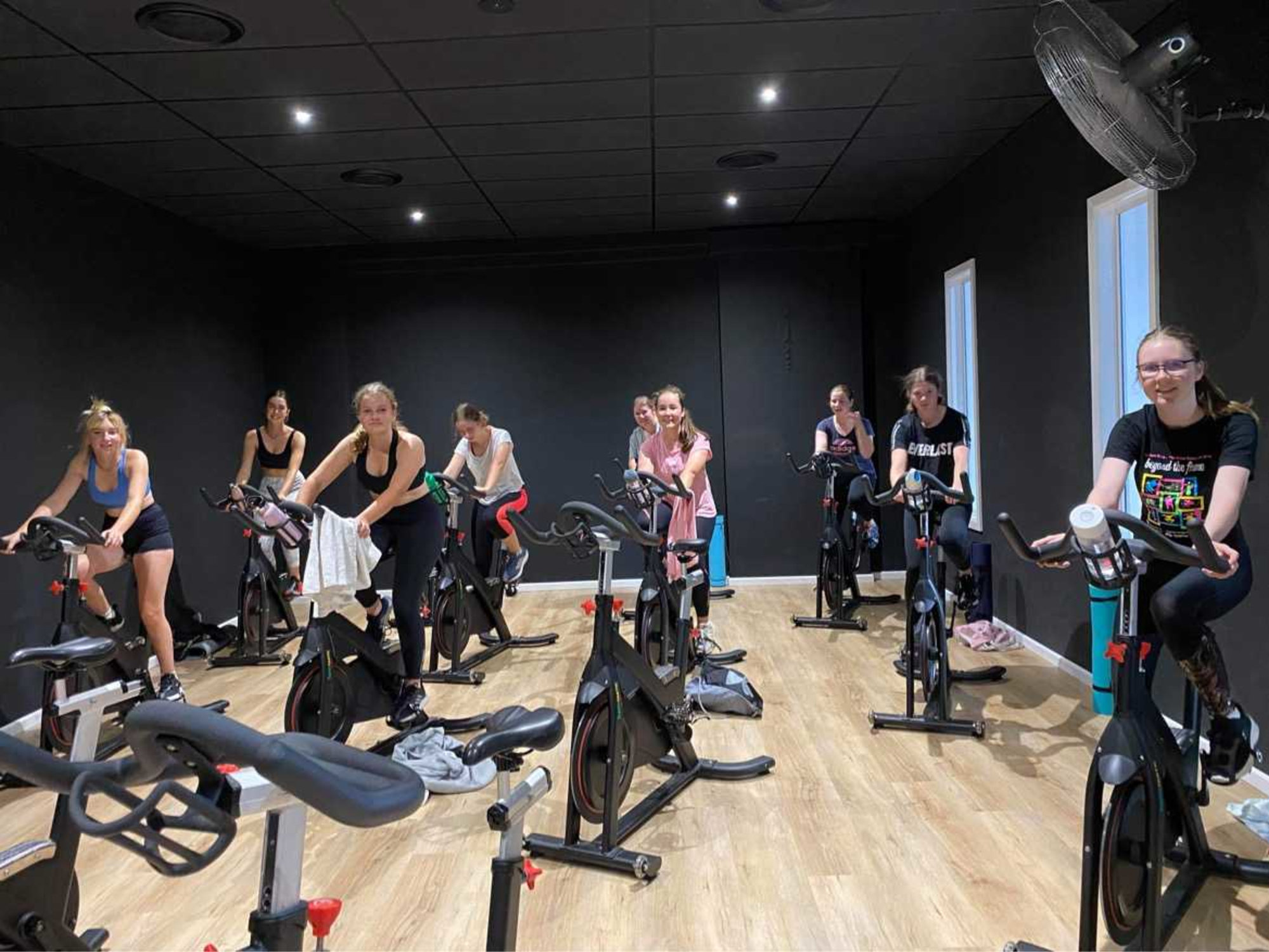 Group of women in a spin class cycling together in a modern indoor studio.