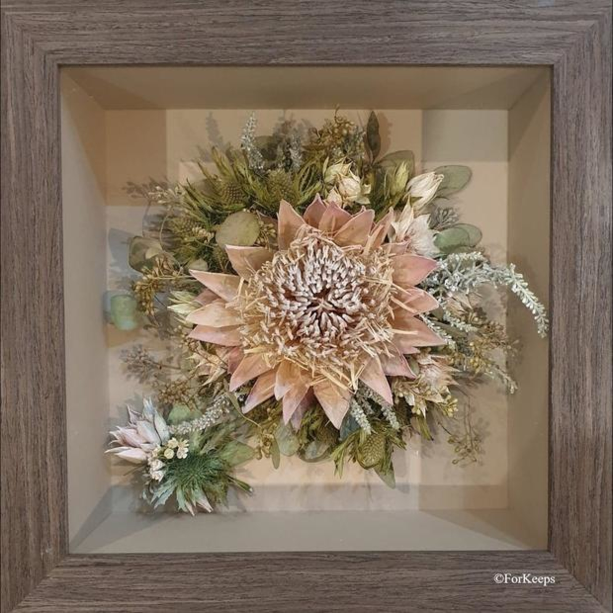 Framed shadow box displaying a preserved wedding bouquet with a large central bloom and surrounding greenery.