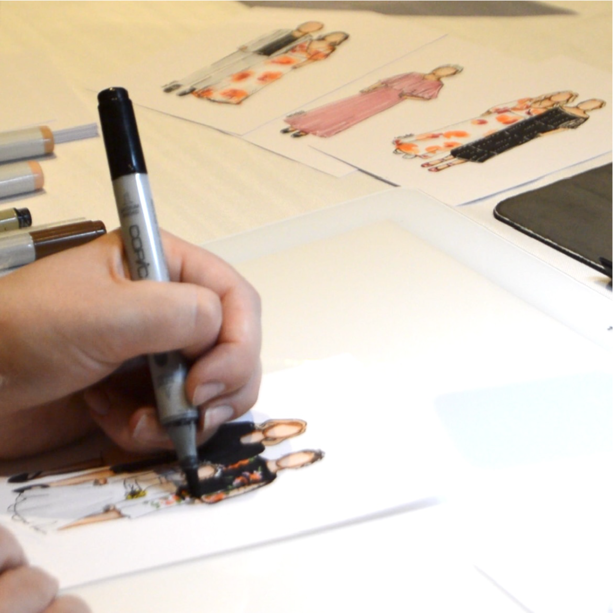 Hand of an artist drawing custom fashion-style portraits of wedding guests on paper.