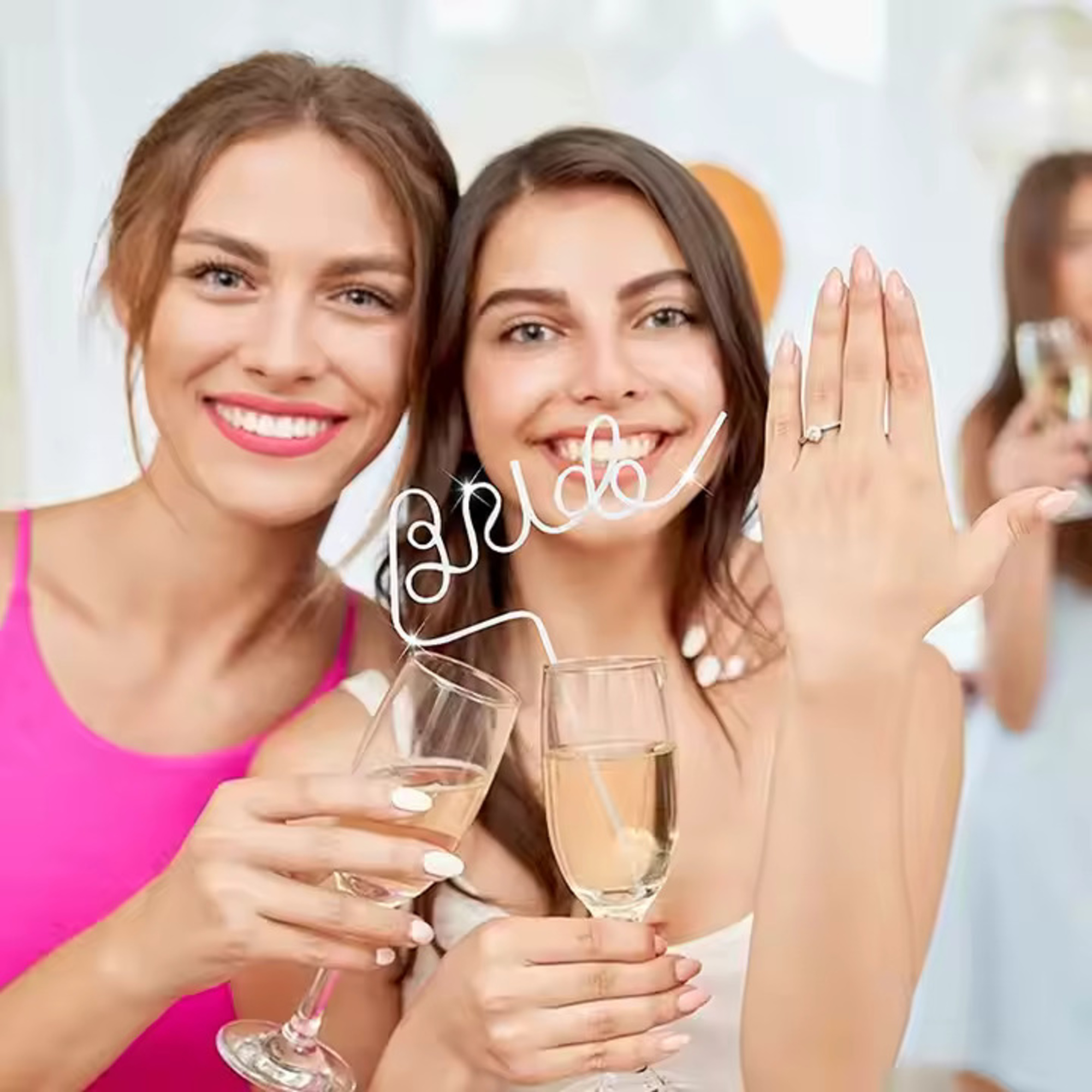 Smiling bride-to-be shows her engagement ring while toasting champagne with a friend at a pre-wedding celebration.