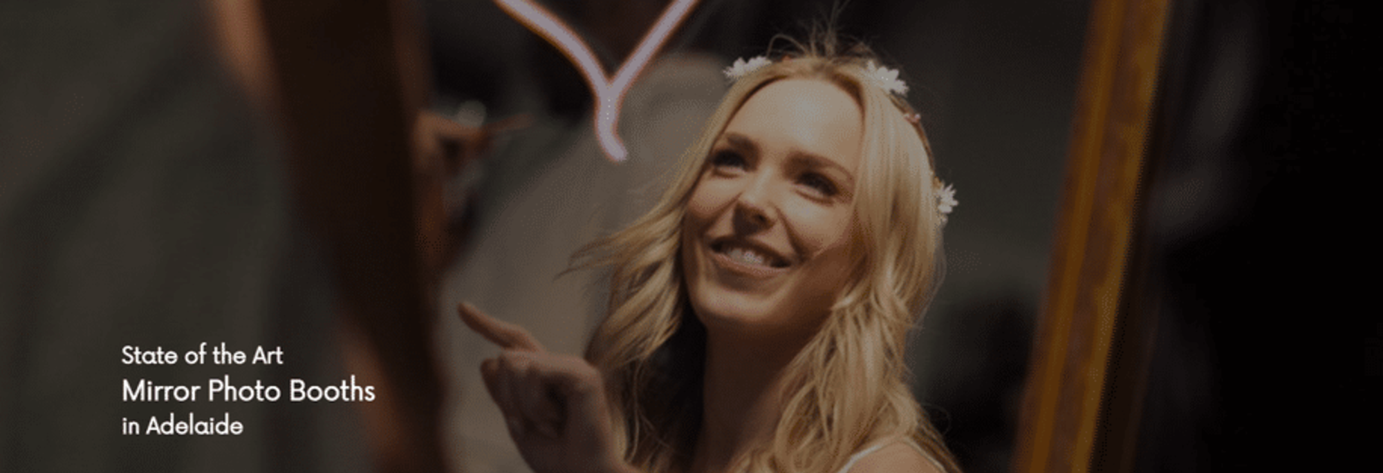 Bride smiles and touches an interactive mirror photo booth at a wedding reception in Adelaide.