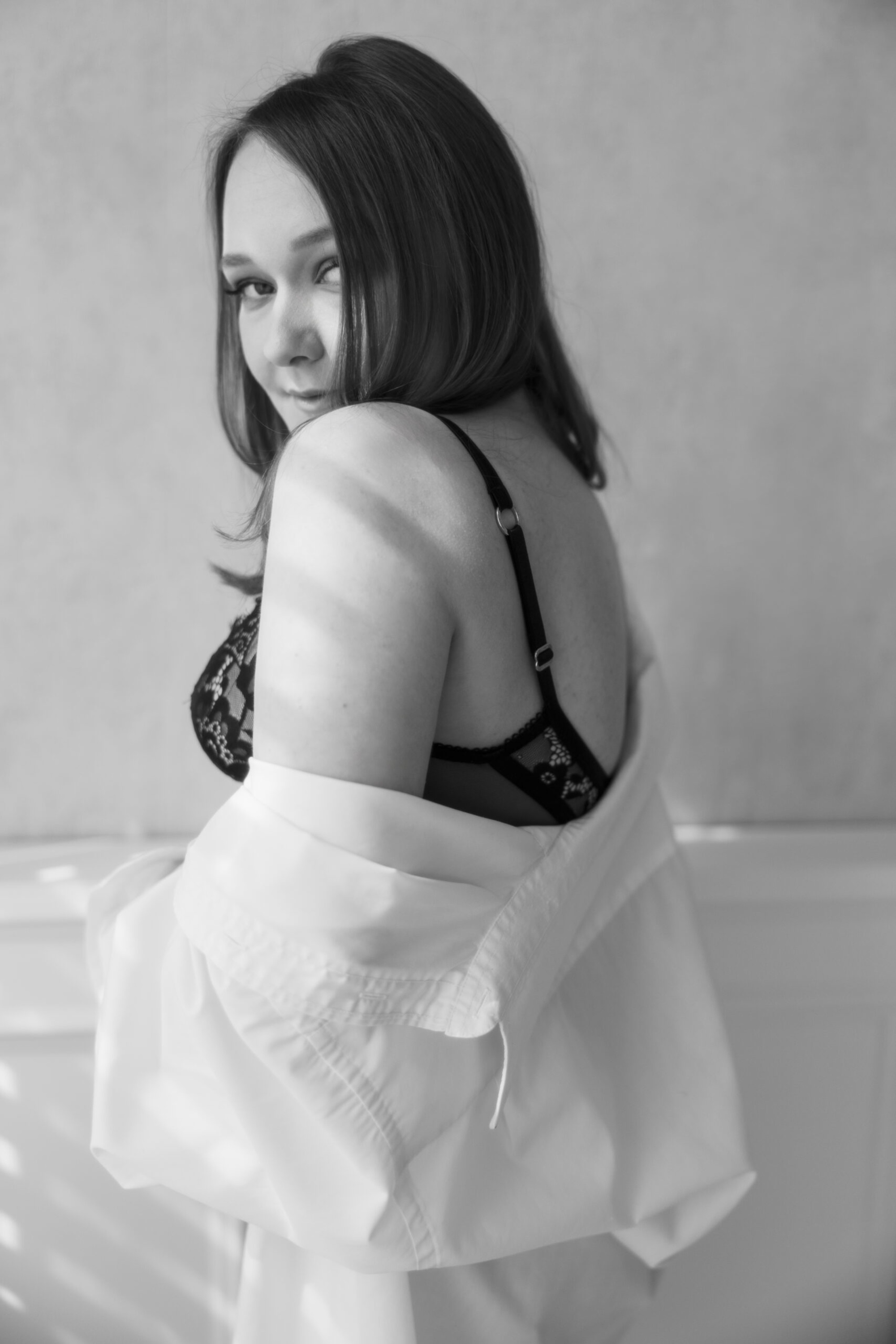 Black and white bridal boudoir portrait of a woman in lingerie with a loose white shirt
