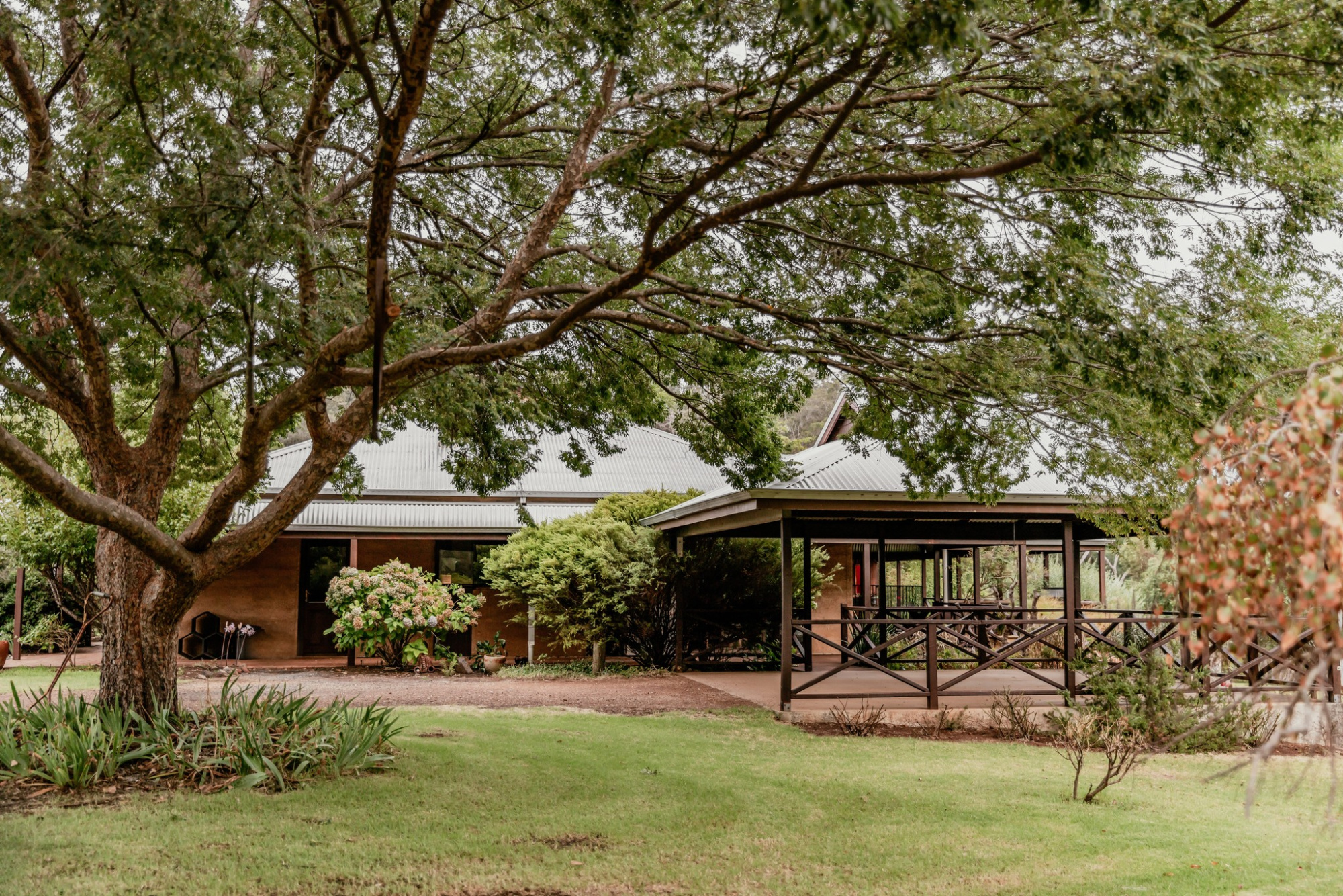 Rustic garden wedding venue with a covered deck surrounded by large trees and lush greenery.