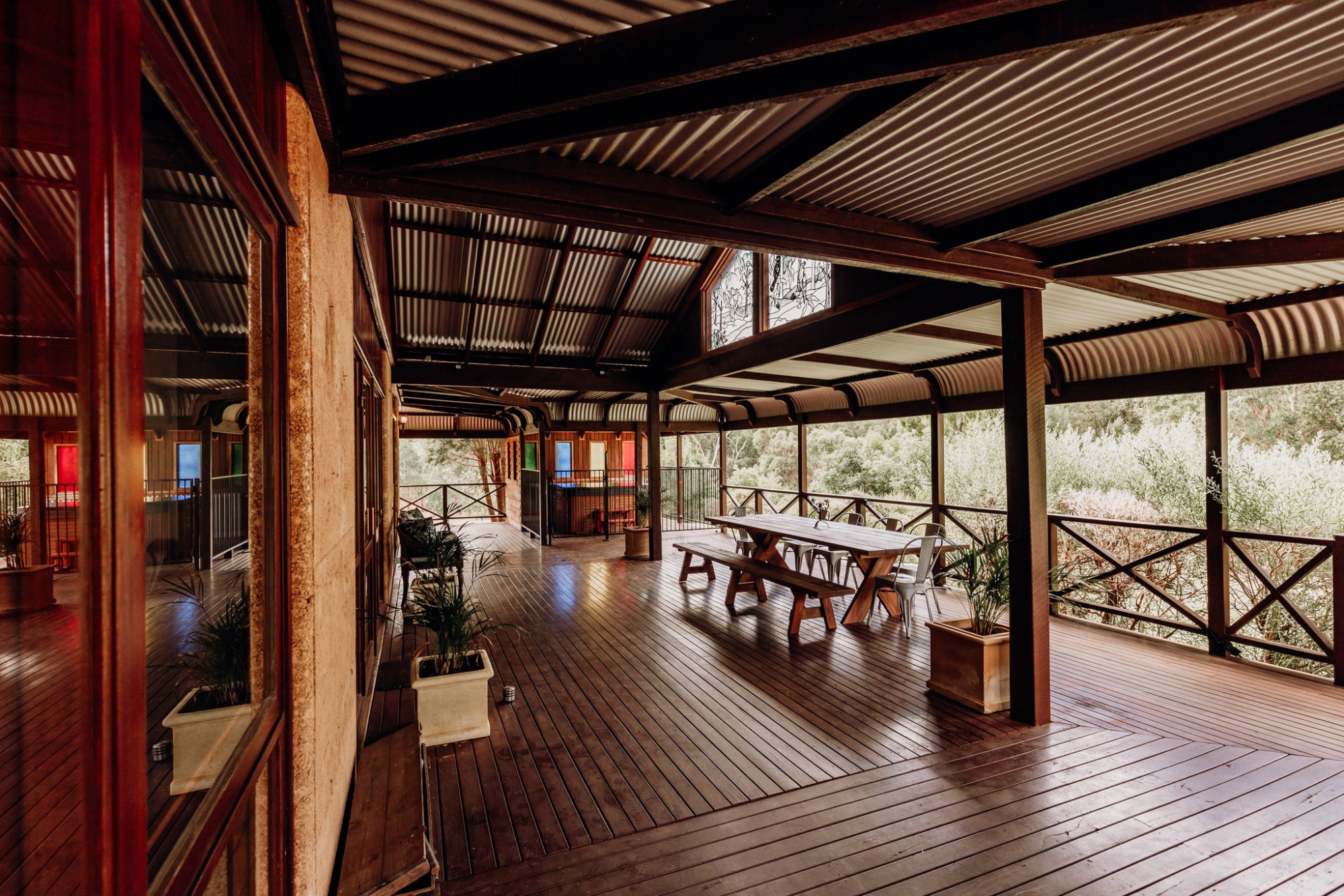 Covered wooden deck with long tables and garden views set for an intimate rustic wedding gathering.