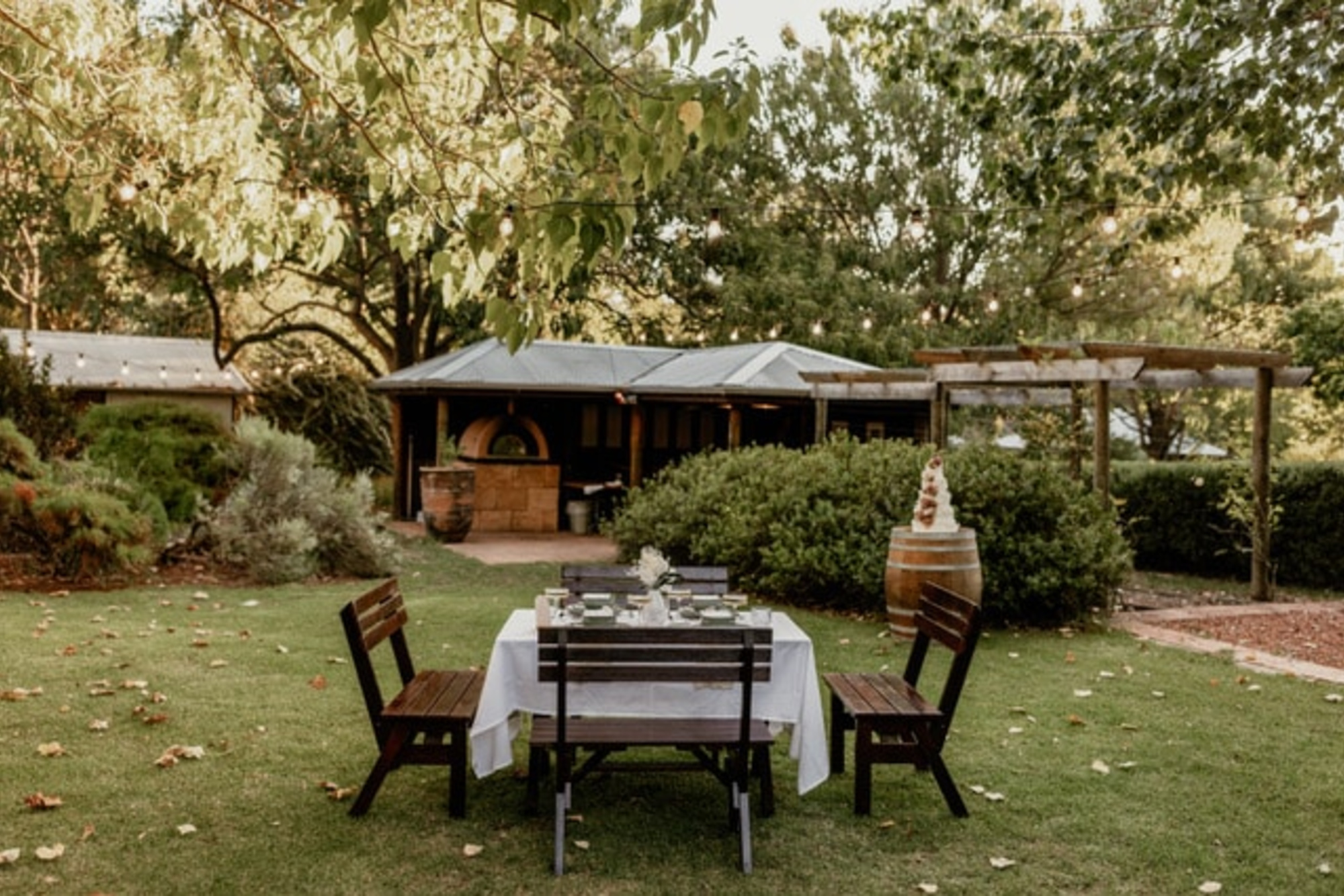 Intimate outdoor wedding table set on a lawn in a rustic garden venue at sunset.