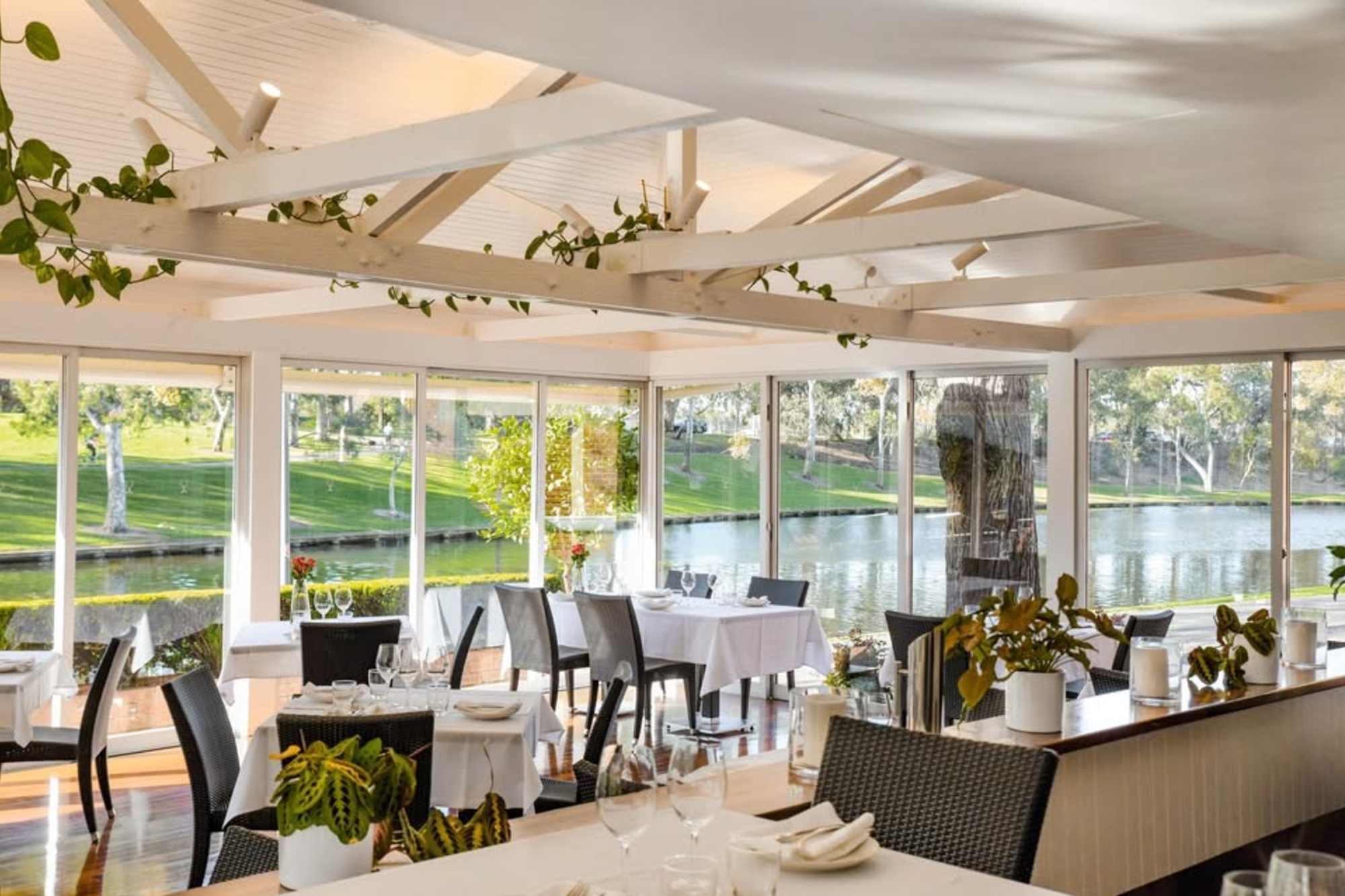 Bright waterfront restaurant-style wedding reception space with large windows and lush greenery views.