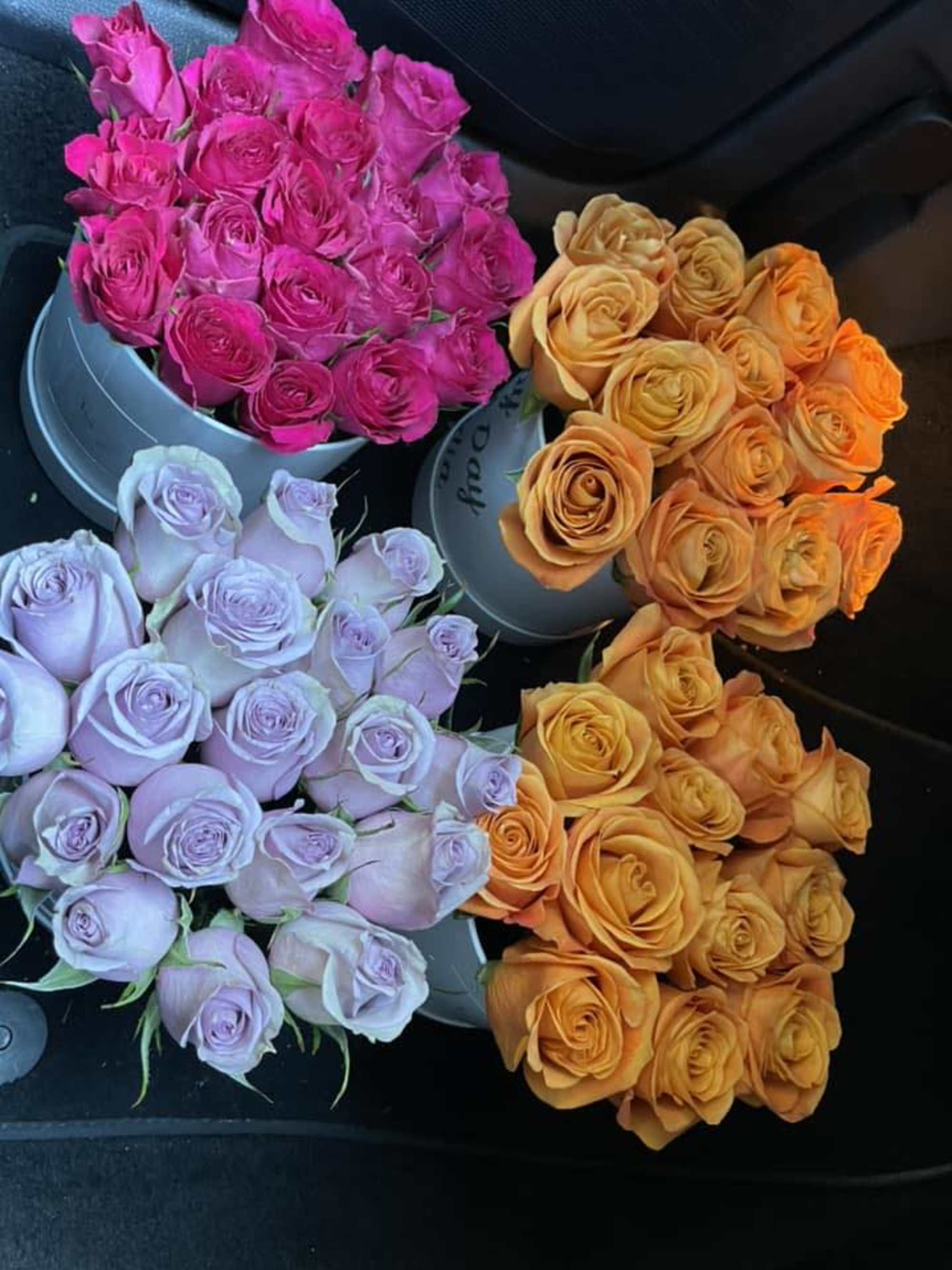 Four buckets filled with pink, lavender, and orange roses arranged for wedding floral decor.