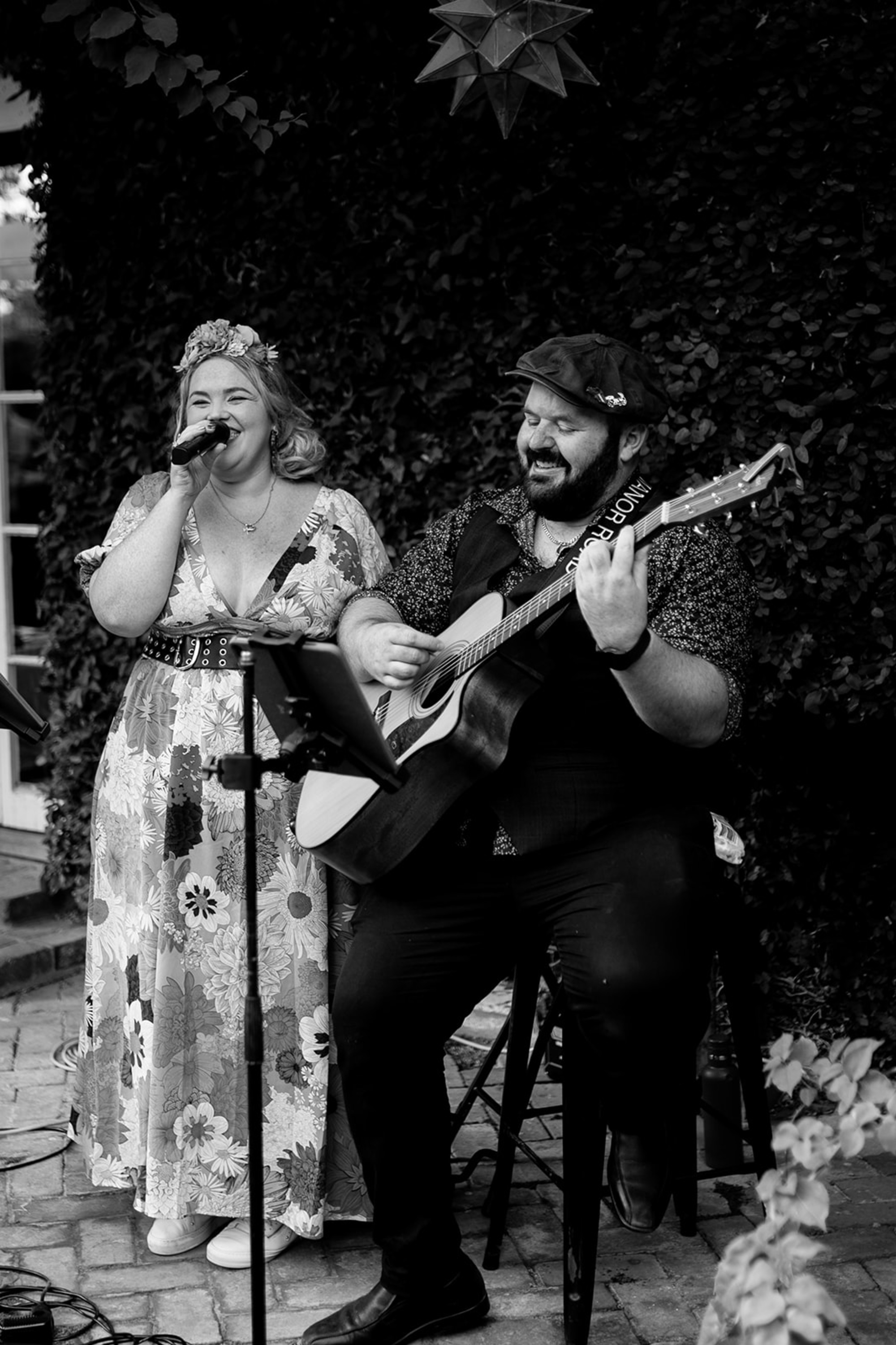 Acoustic singer and guitarist performing together at an outdoor wedding reception.
