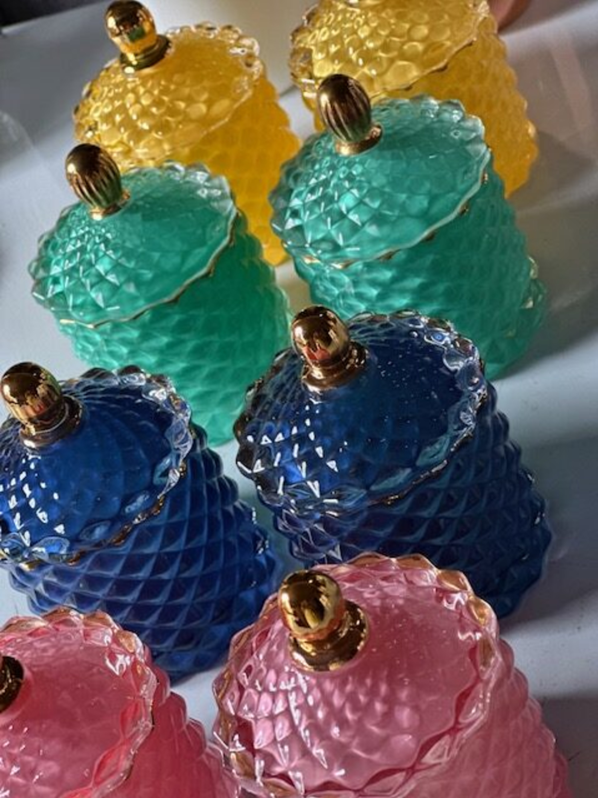 Colorful textured glass jars with gold lids arranged together for wedding favor or table decor.