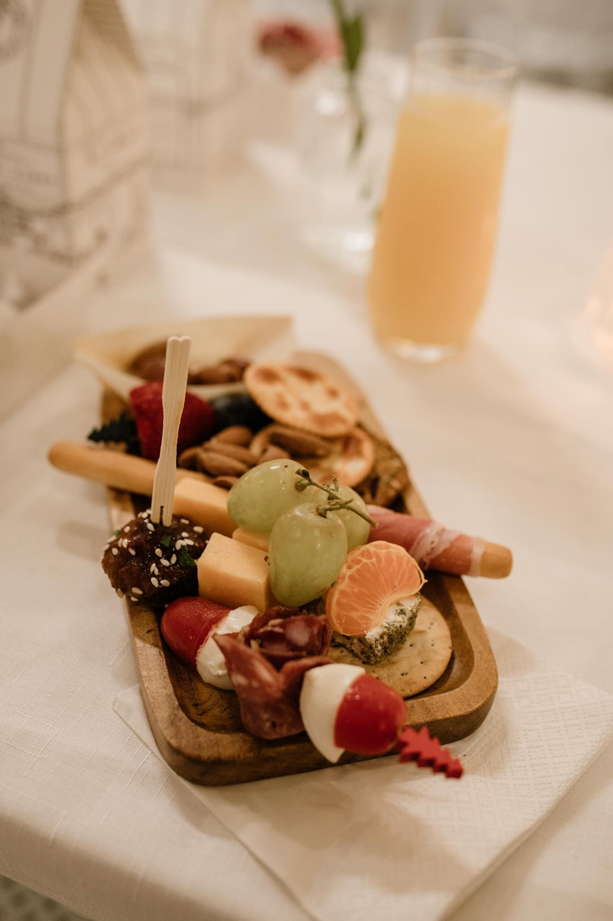 Elegant charcuterie board with fruit, cheese, meats, and crackers on a wedding reception table.