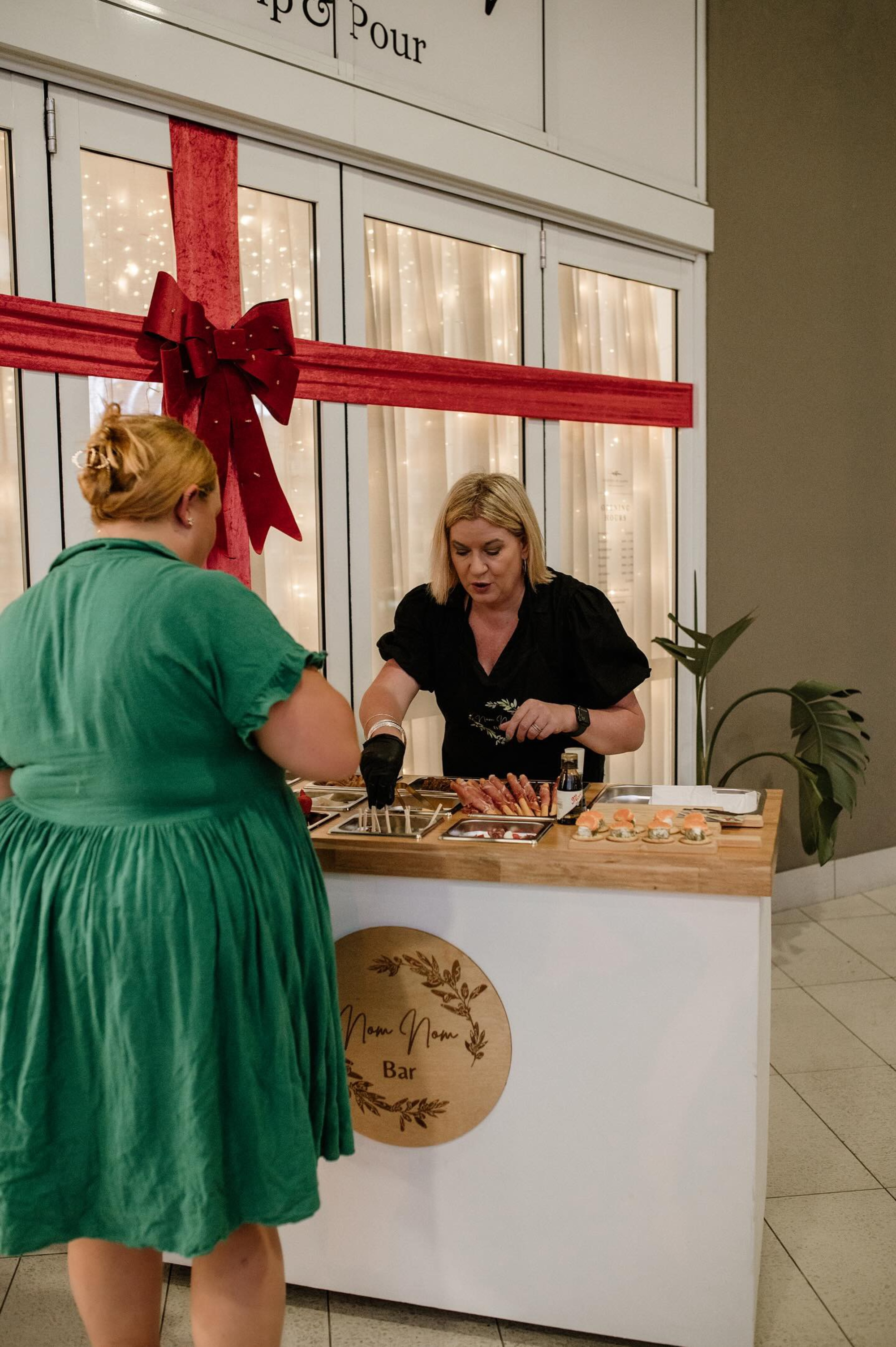 Caterer serving canapés from a Nom Nom Bar food station decorated for a wedding or event.