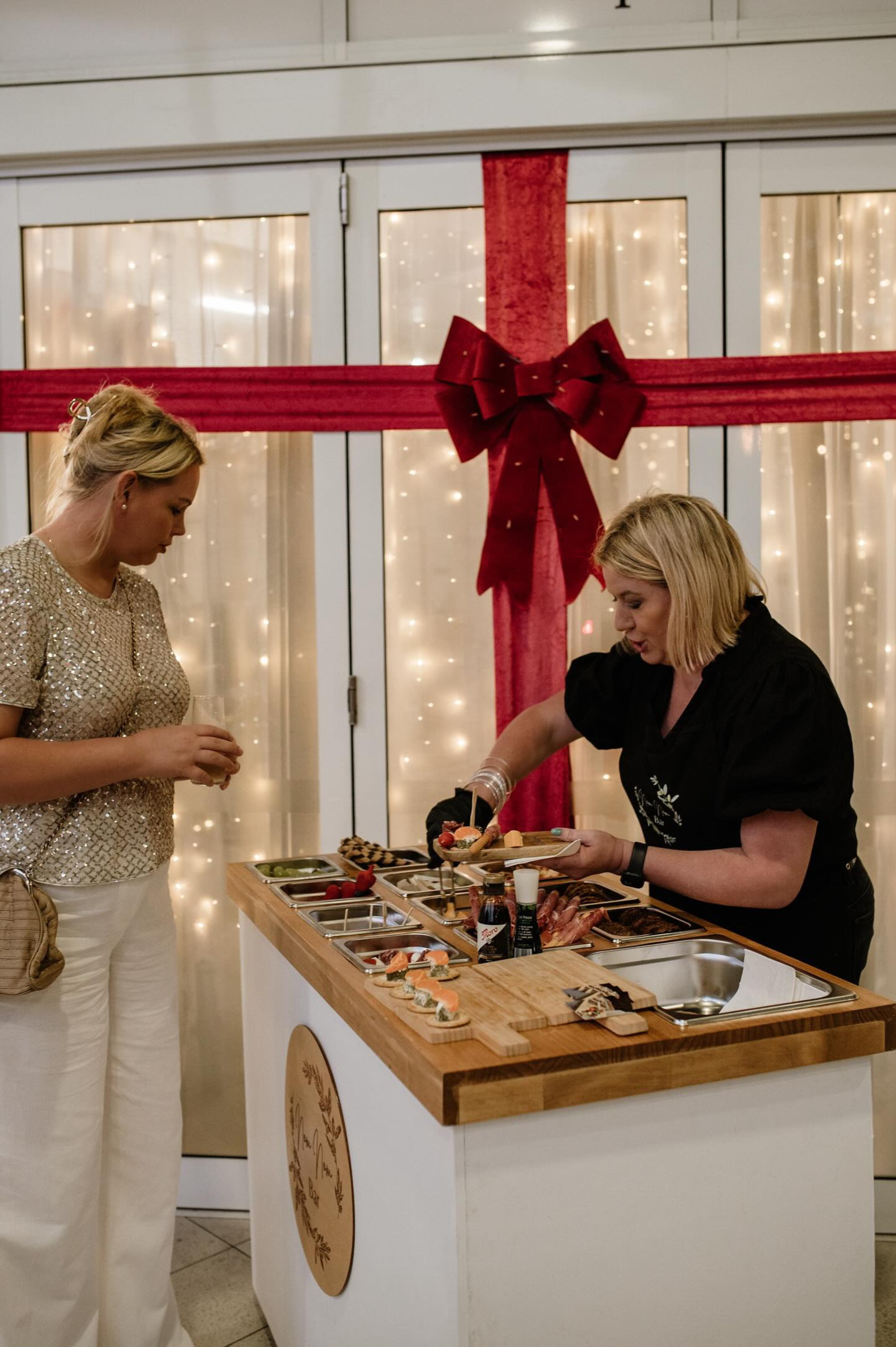 Caterer prepares elegant bite-sized appetizers for a guest at a decorated wedding food station.