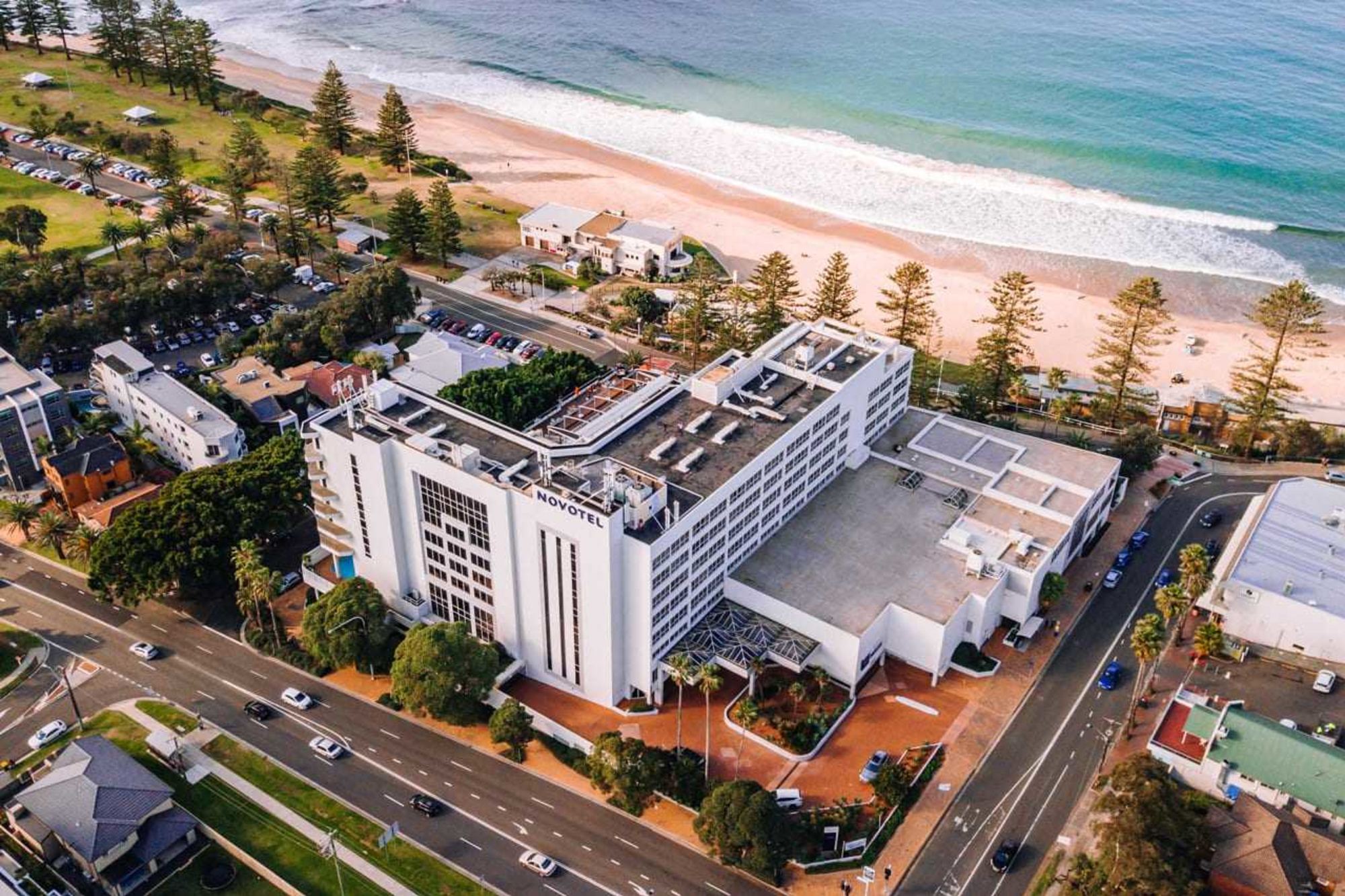 Aerial view of a large beachfront hotel and surrounding coastal area beside the ocean.