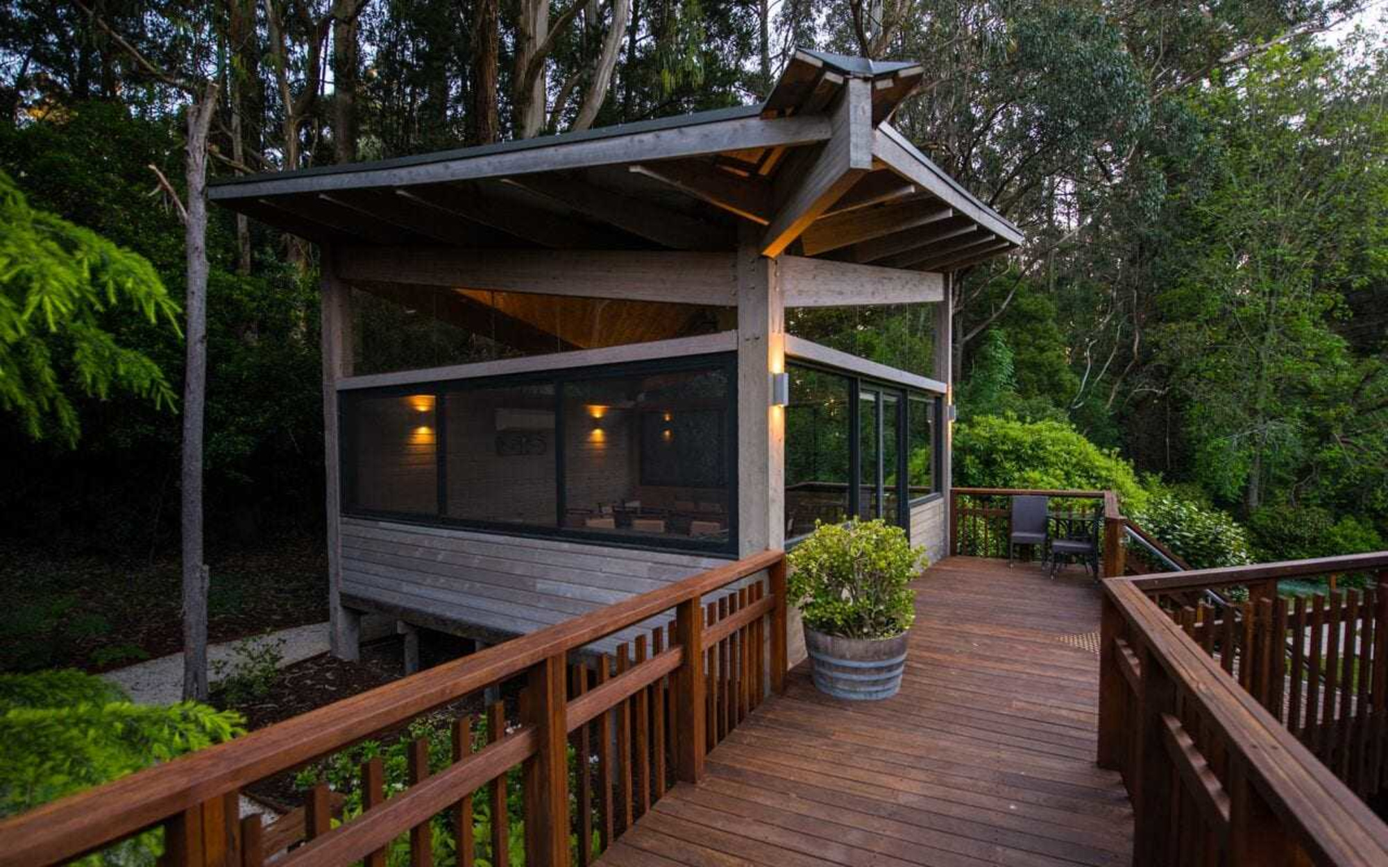 Modern wooden cabin with large deck surrounded by lush forest, set up as an intimate wedding venue.