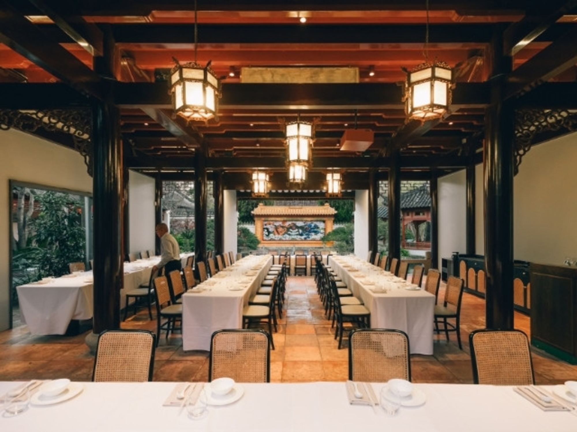 Elegant indoor wedding reception space with long banquet tables in an Asian-inspired venue.