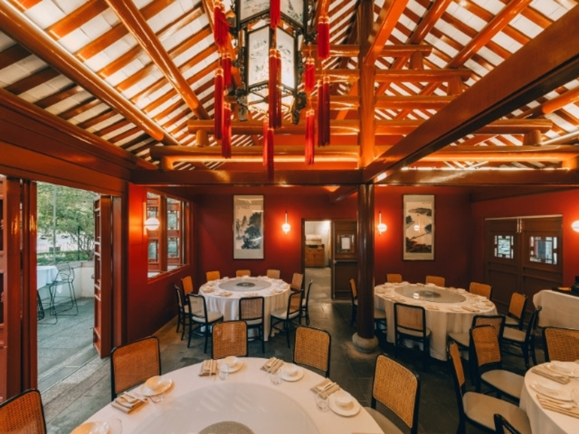 Warmly lit Asian-style banquet room with round tables set for an intimate wedding reception.