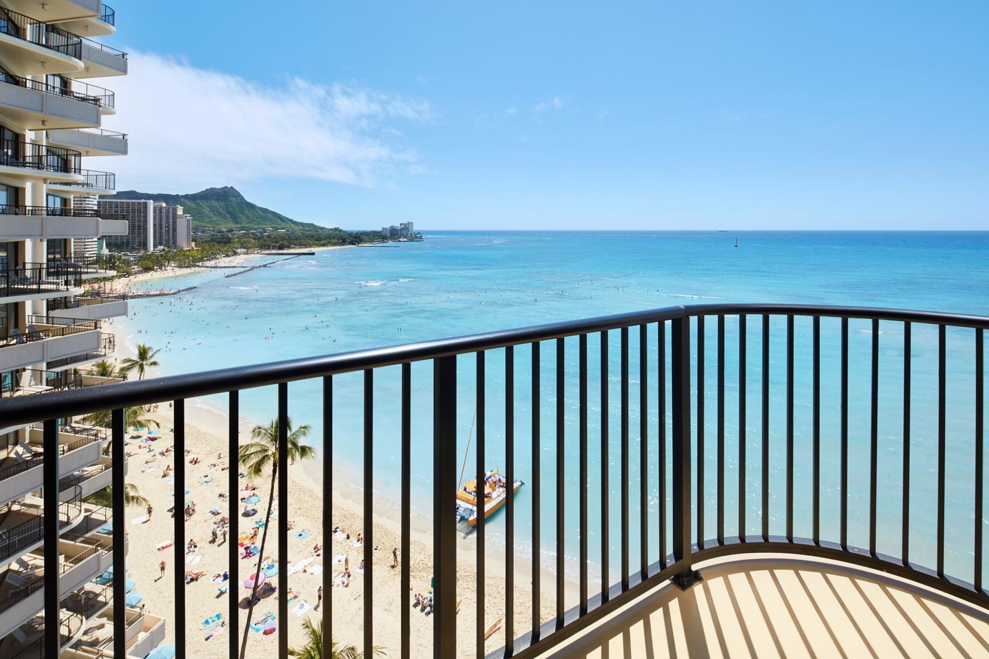 Oceanfront hotel balcony overlooking a tropical beach and turquoise water on a sunny day.