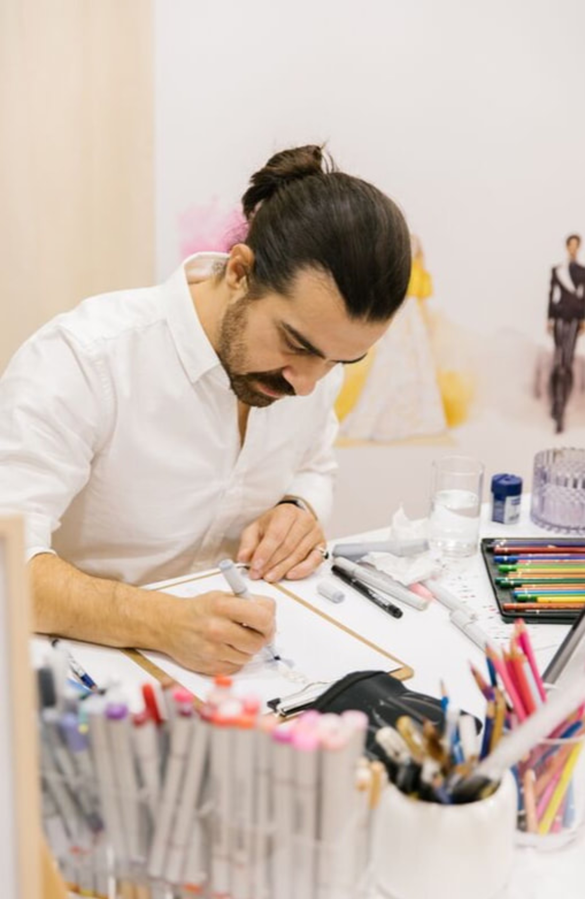 Wedding artist creates a custom illustration at a desk filled with colorful markers and pencils.