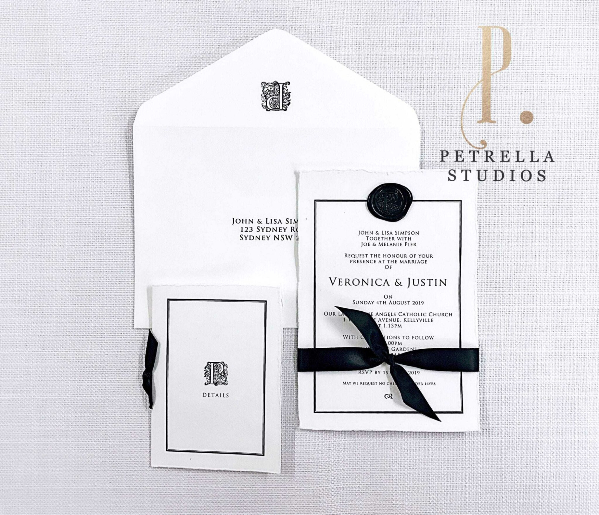Flat lay of elegant black and white wedding invitation suite with wax seal and ribbon by Petrella Studios.