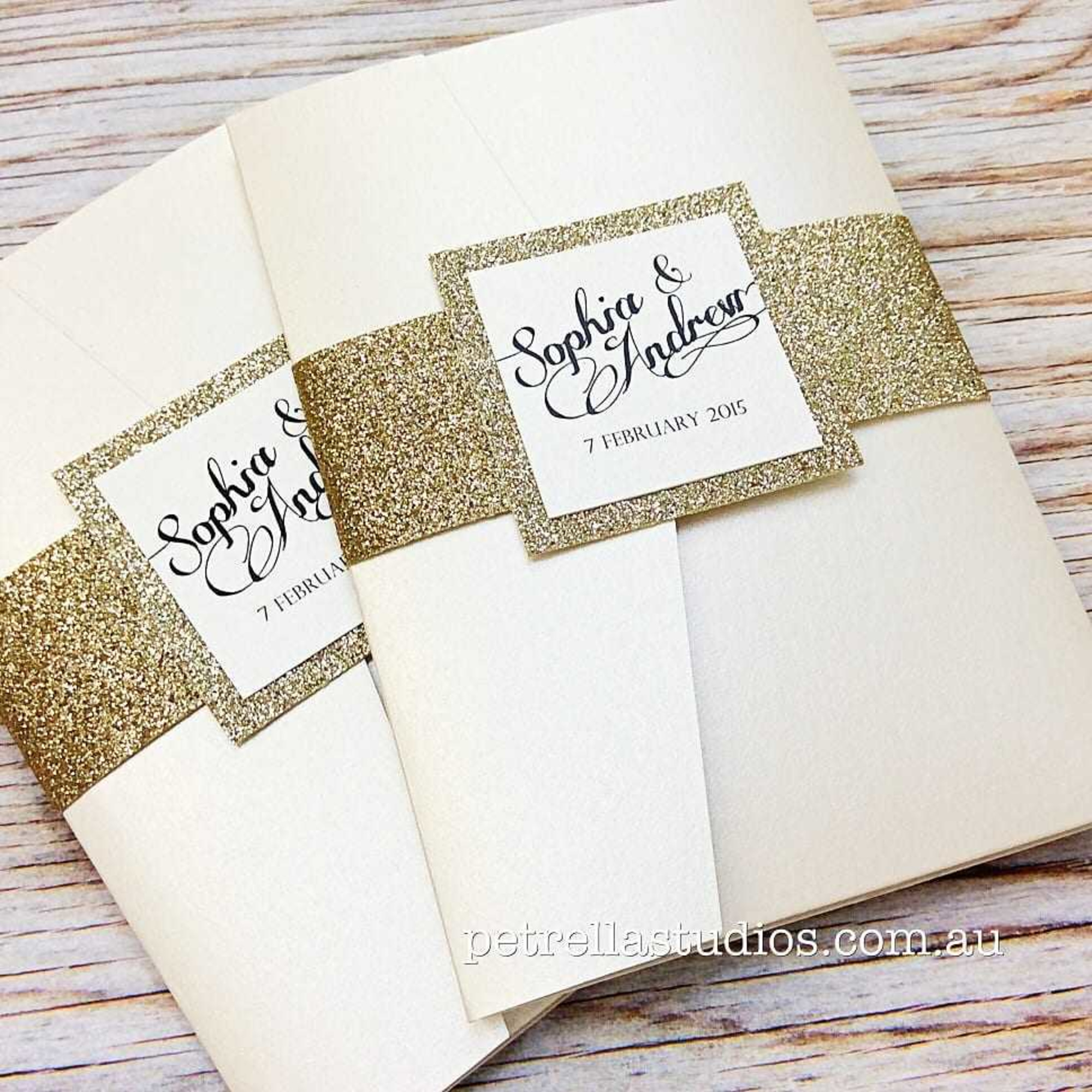 Elegant cream wedding invitations wrapped with gold glitter belly bands and calligraphy name cards.