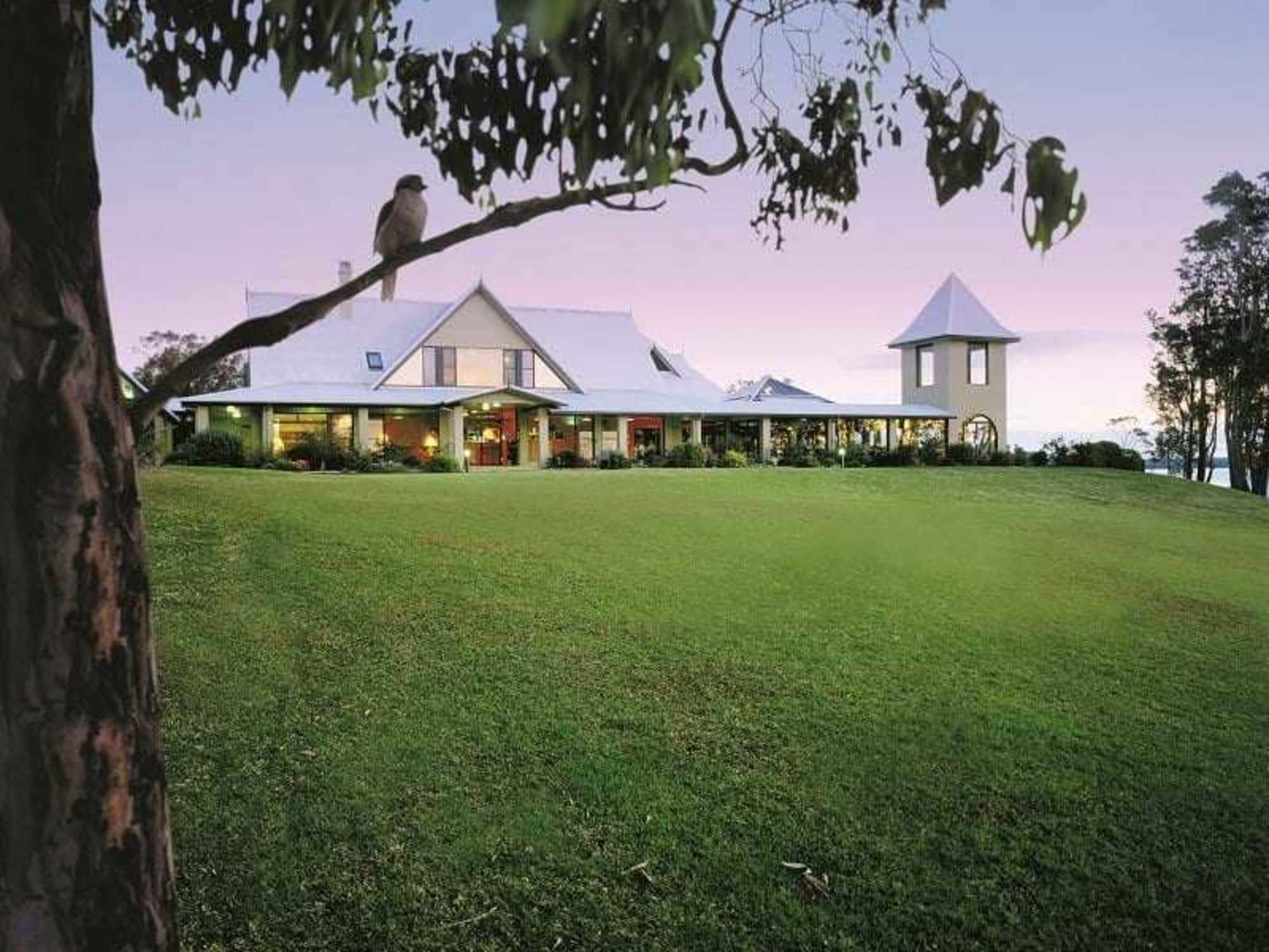 Country estate wedding venue with wide green lawn and tower at sunset.