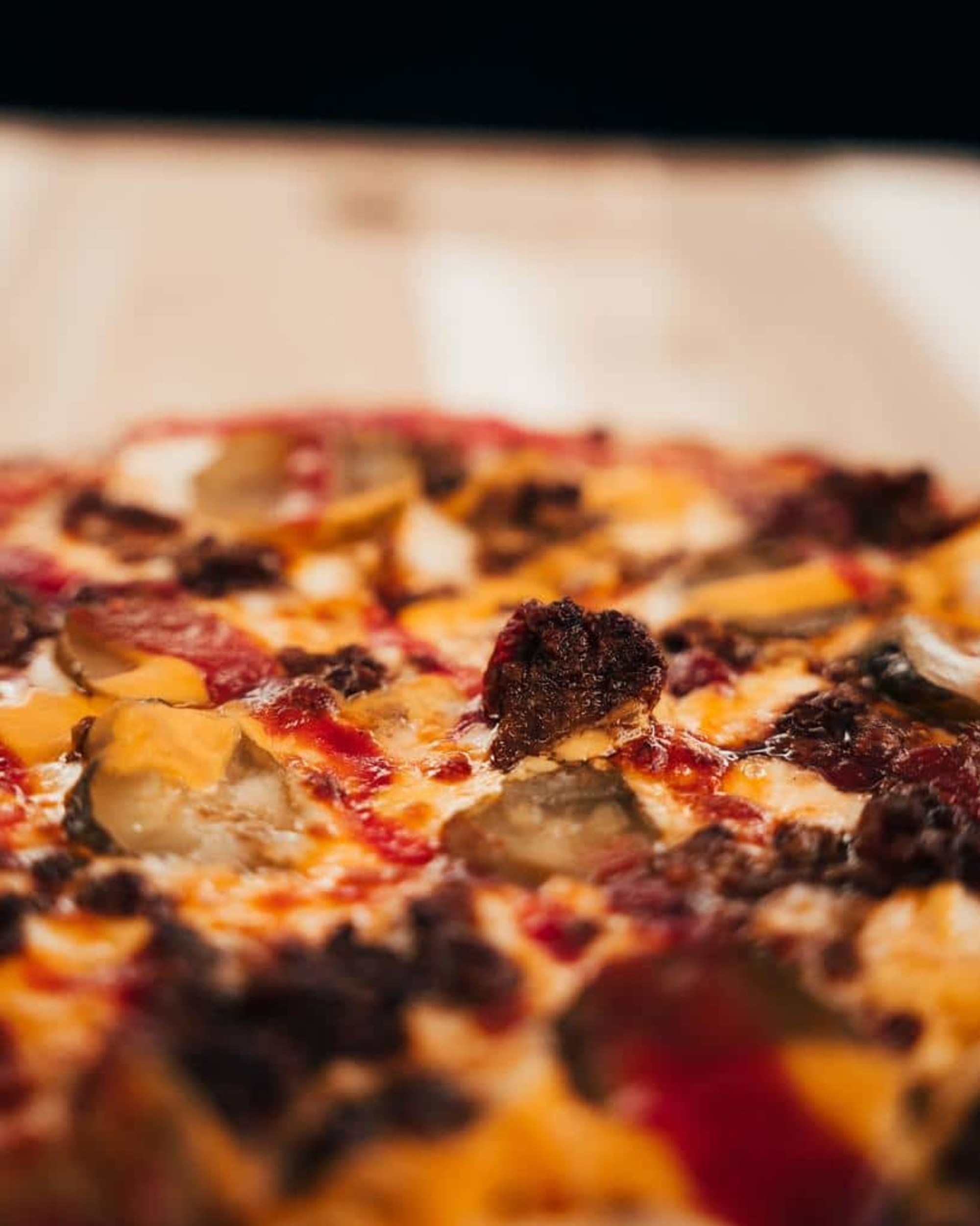 Close-up of a cheesy meat-topped pizza, ideal as casual wedding reception catering.