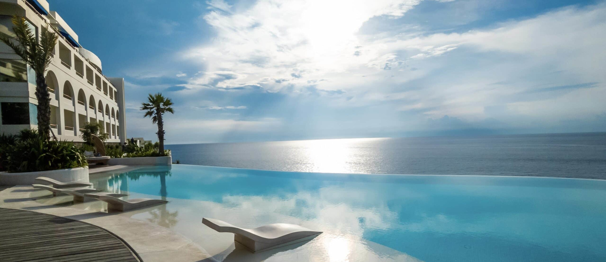 Oceanfront luxury resort with infinity pool overlooking the sea at sunset, ideal for a destination wedding venue.
