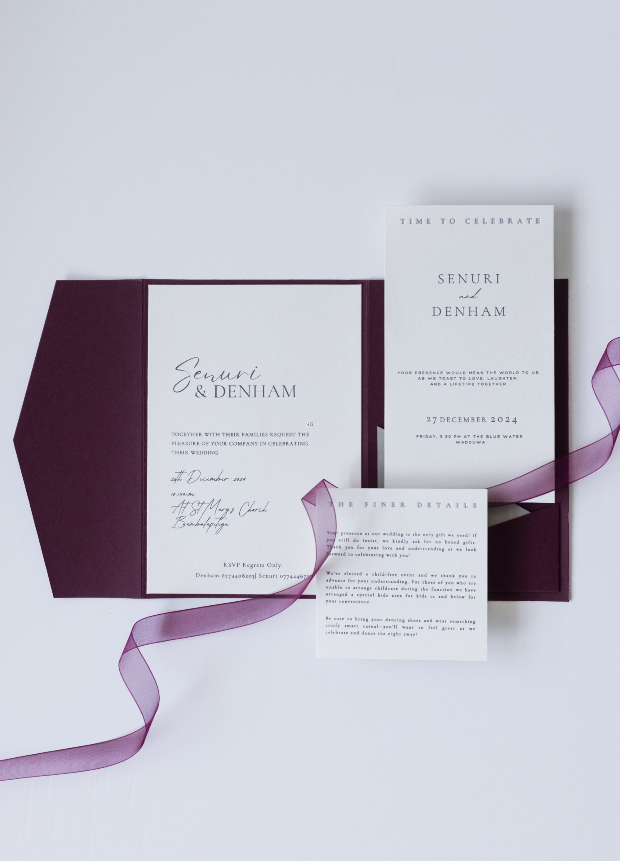 Flatlay of a minimalist burgundy and white wedding invitation suite with ribbon accents.