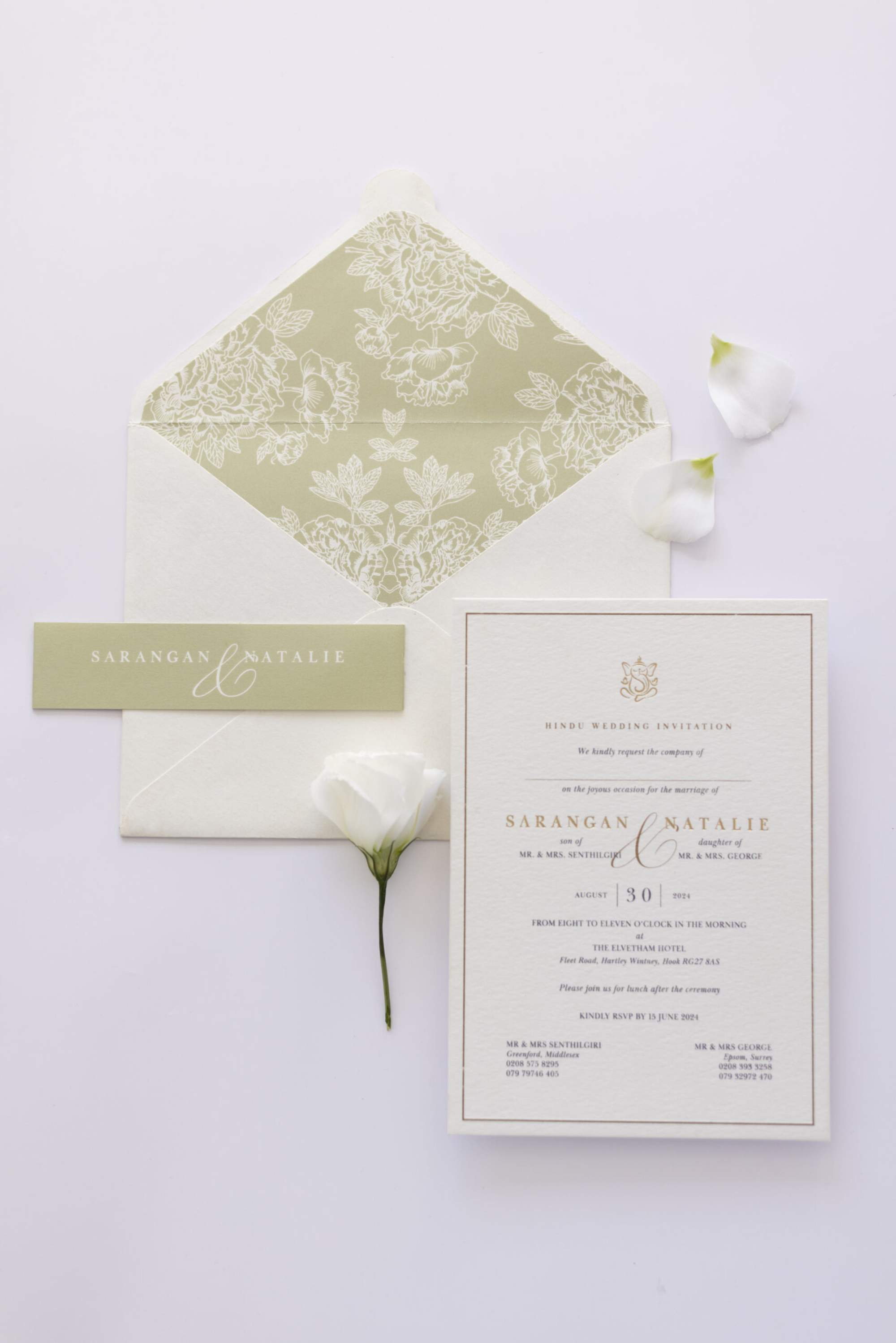 Elegant wedding invitation suite with floral envelope liner, name card, and white flower on a light background.