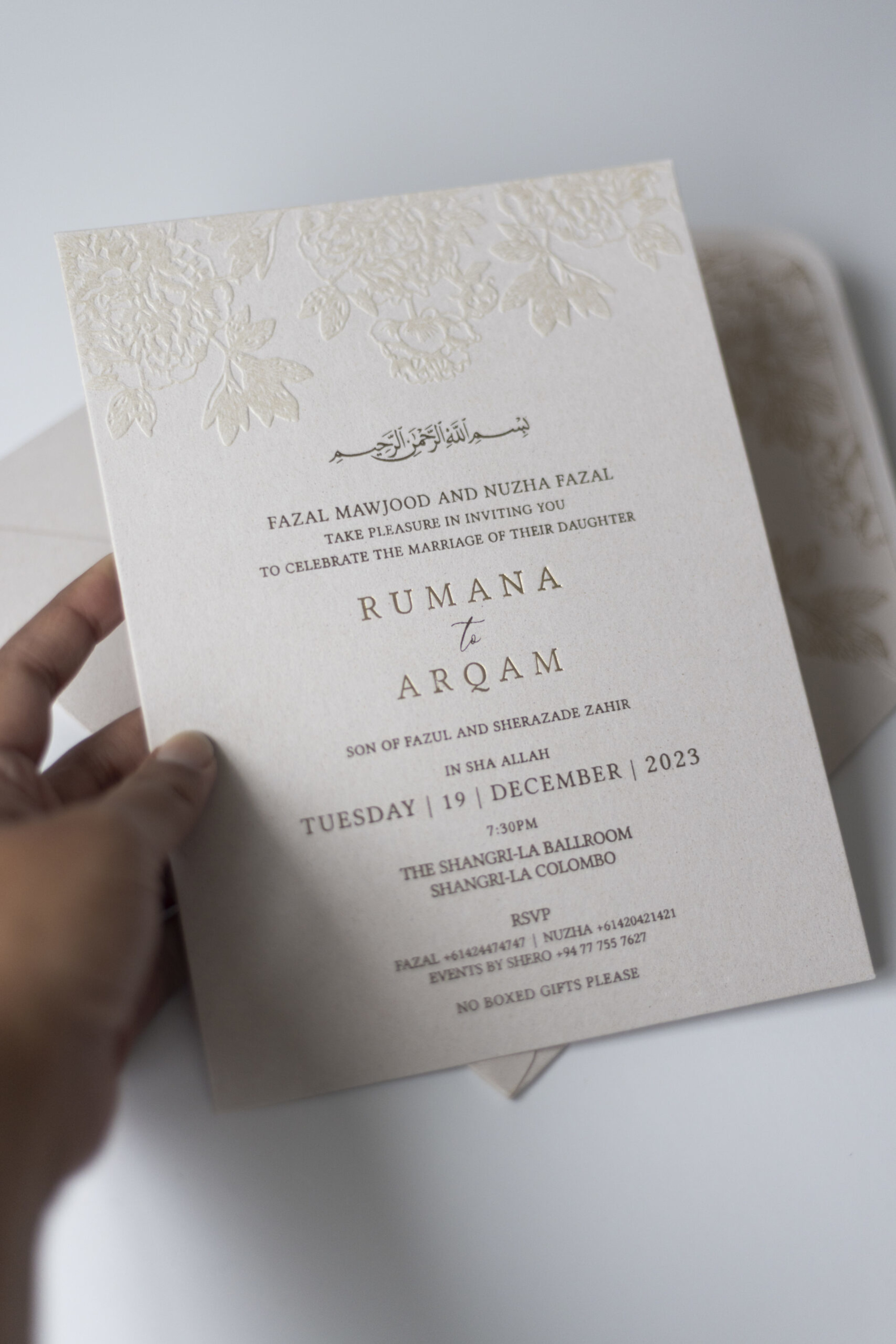 Elegant cream wedding invitation card with embossed floral border and modern serif typography.
