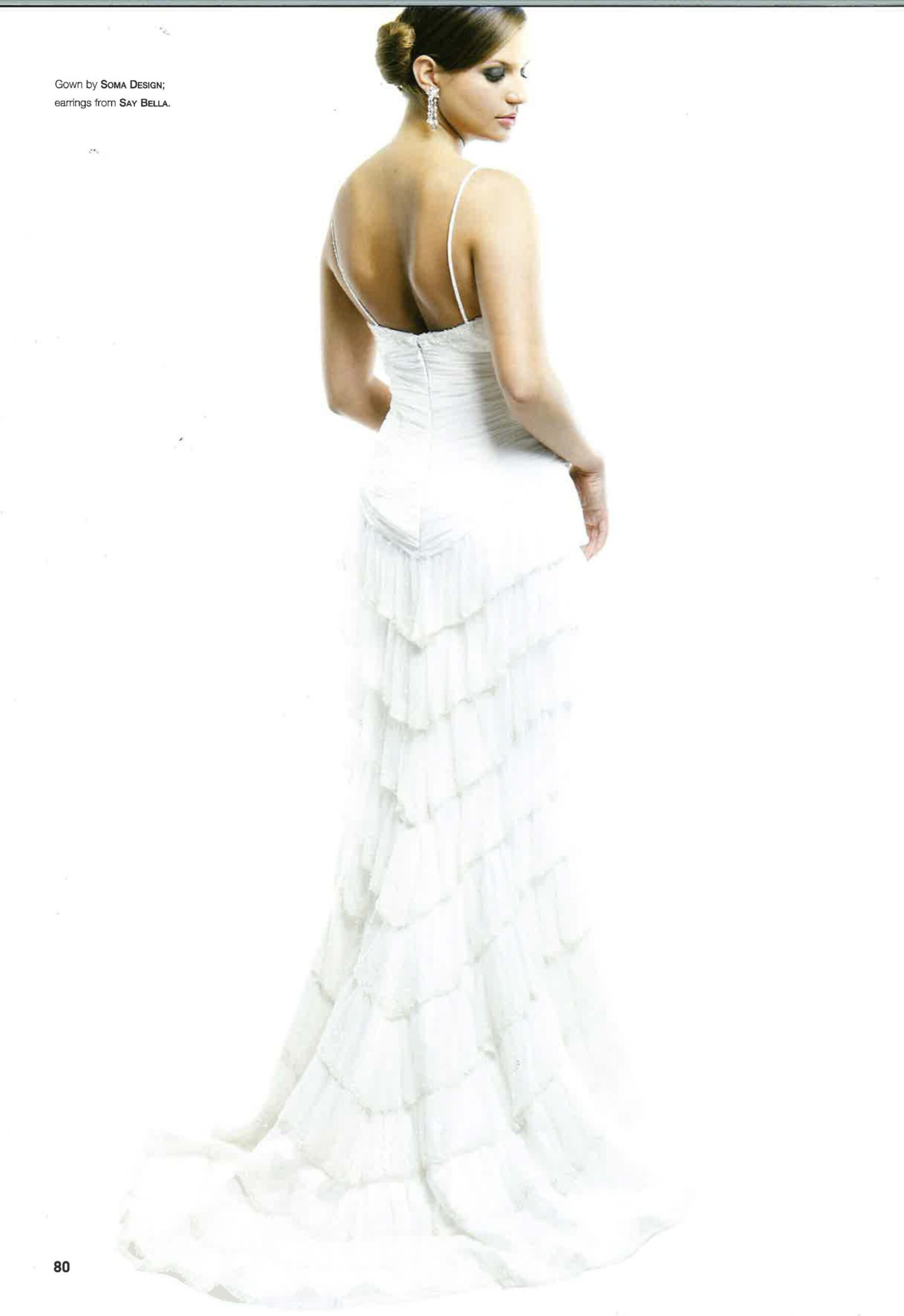 Elegant bride in a stunning white tiered wedding gown with delicate spaghetti straps and sparkling earrings.