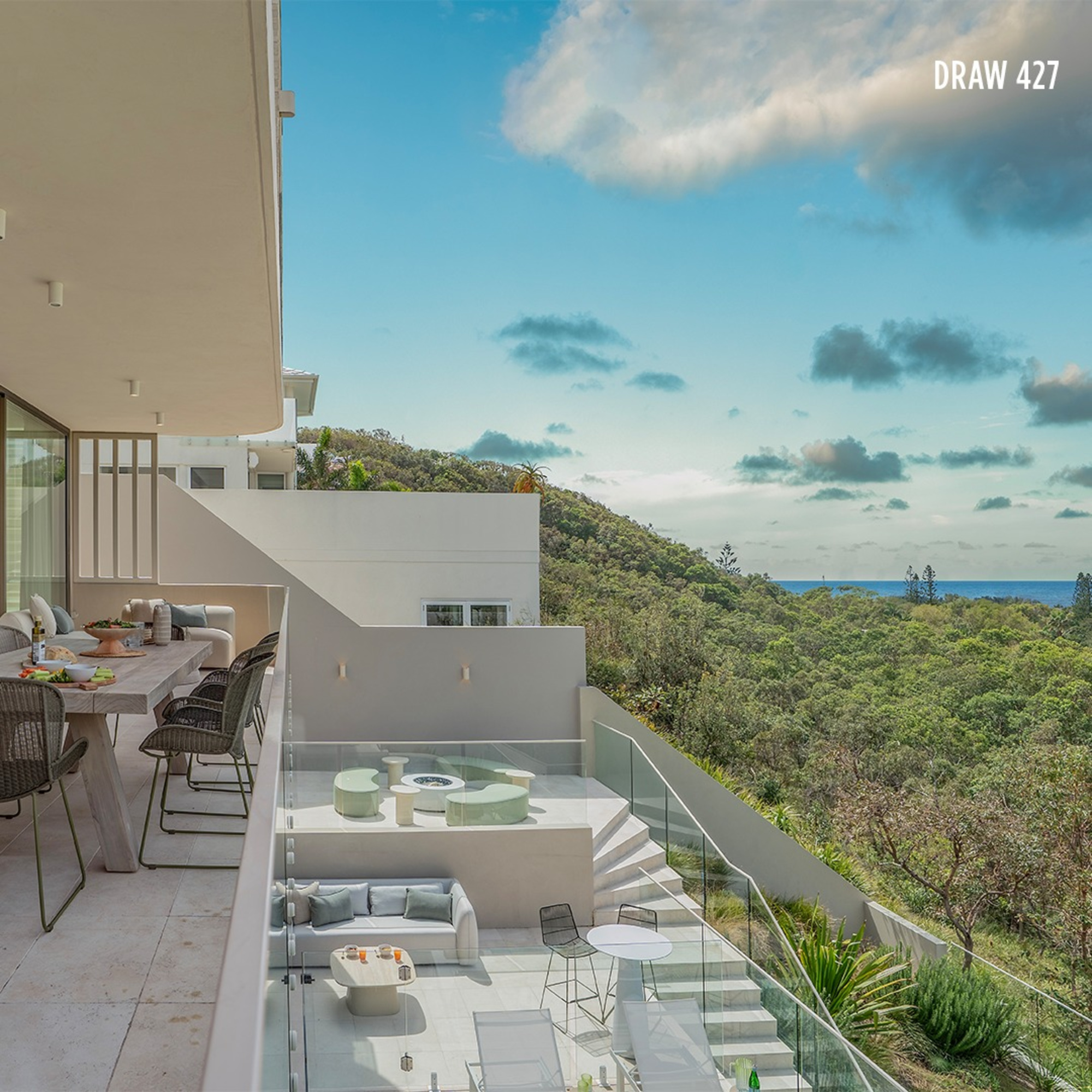 Modern multi-level terrace venue overlooking lush hills and distant ocean under a bright sky.