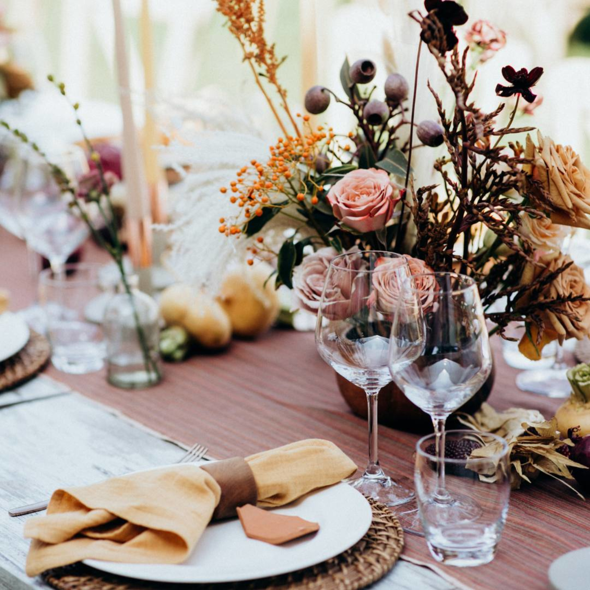Rustic wedding reception table with floral centerpiece, glassware, and neutral-toned place settings.