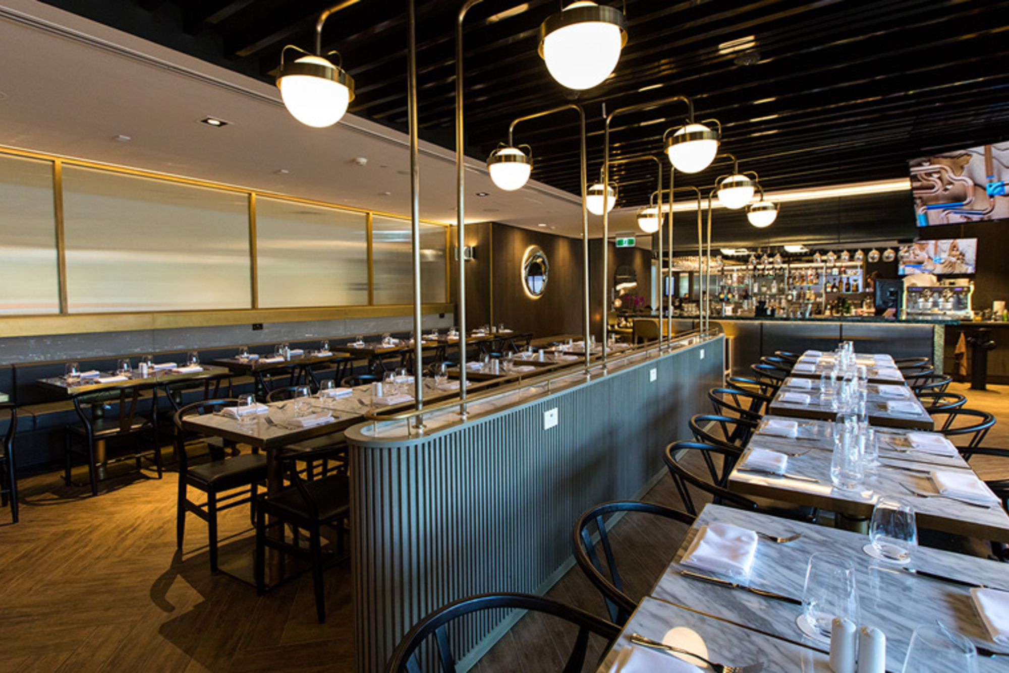 Modern restaurant dining room set for a wedding reception with long tables and ambient lighting.