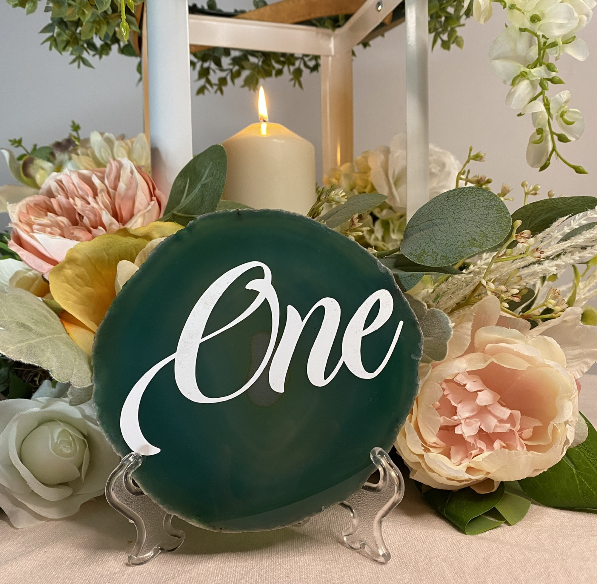 Green agate table number sign reading One styled with flowers and a candle centerpiece.