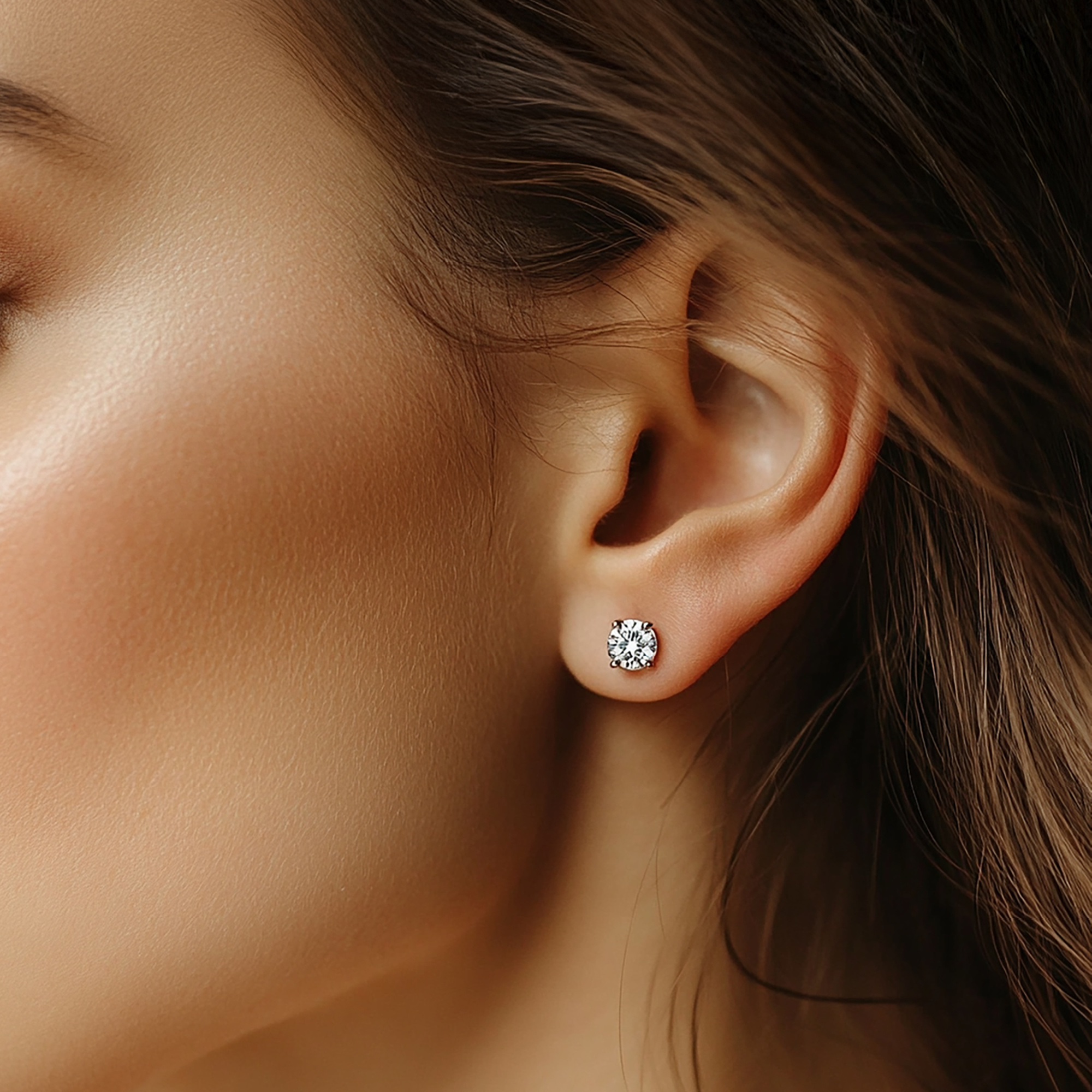 Close-up of a woman wearing a single diamond stud earring, highlighting elegant bridal jewelry.