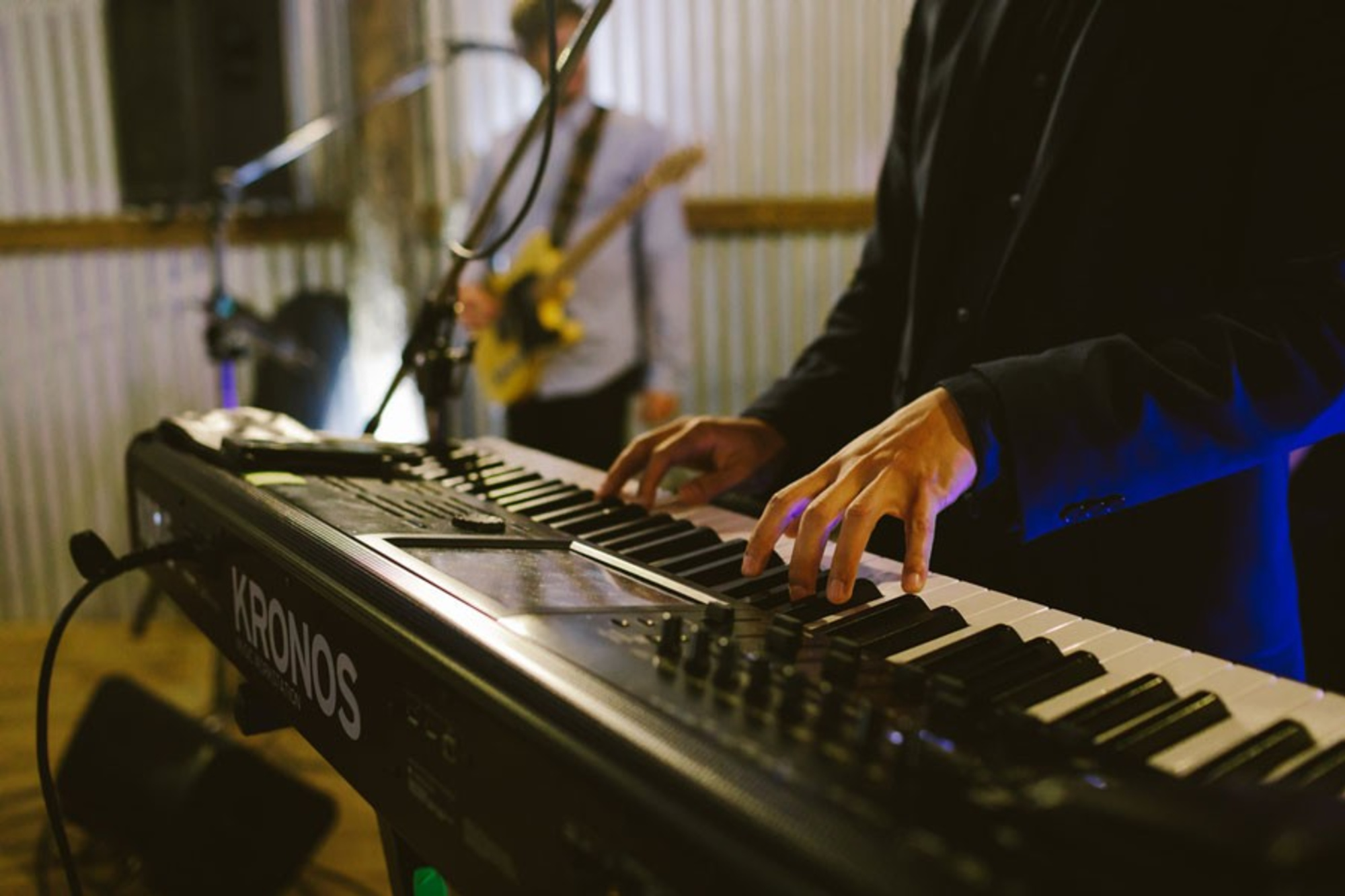 Close-up of a keyboard player performing with a live band at a wedding reception.