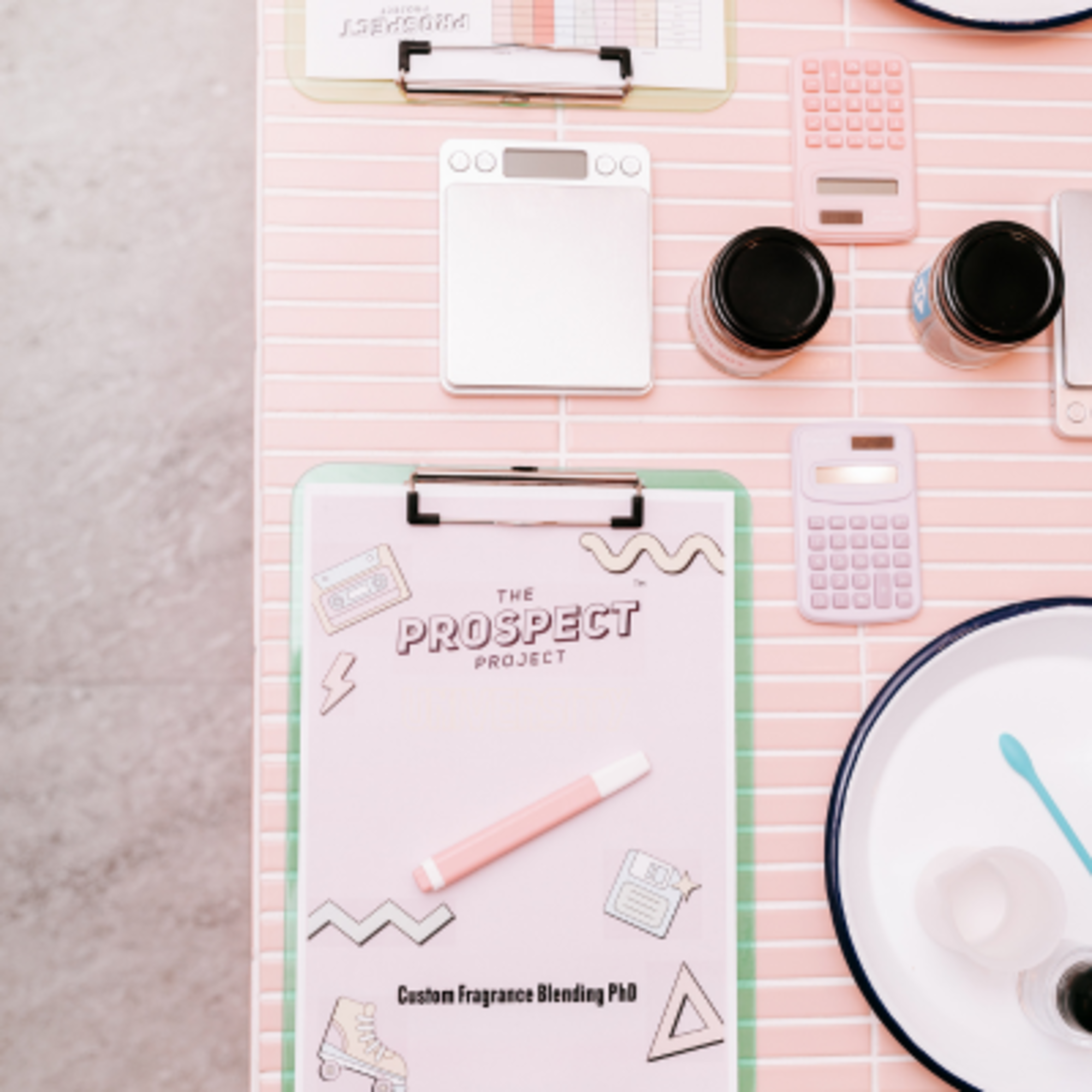 Pastel-toned wedding workshop table with clipboards, calculators, jars, and stationery arranged neatly.
