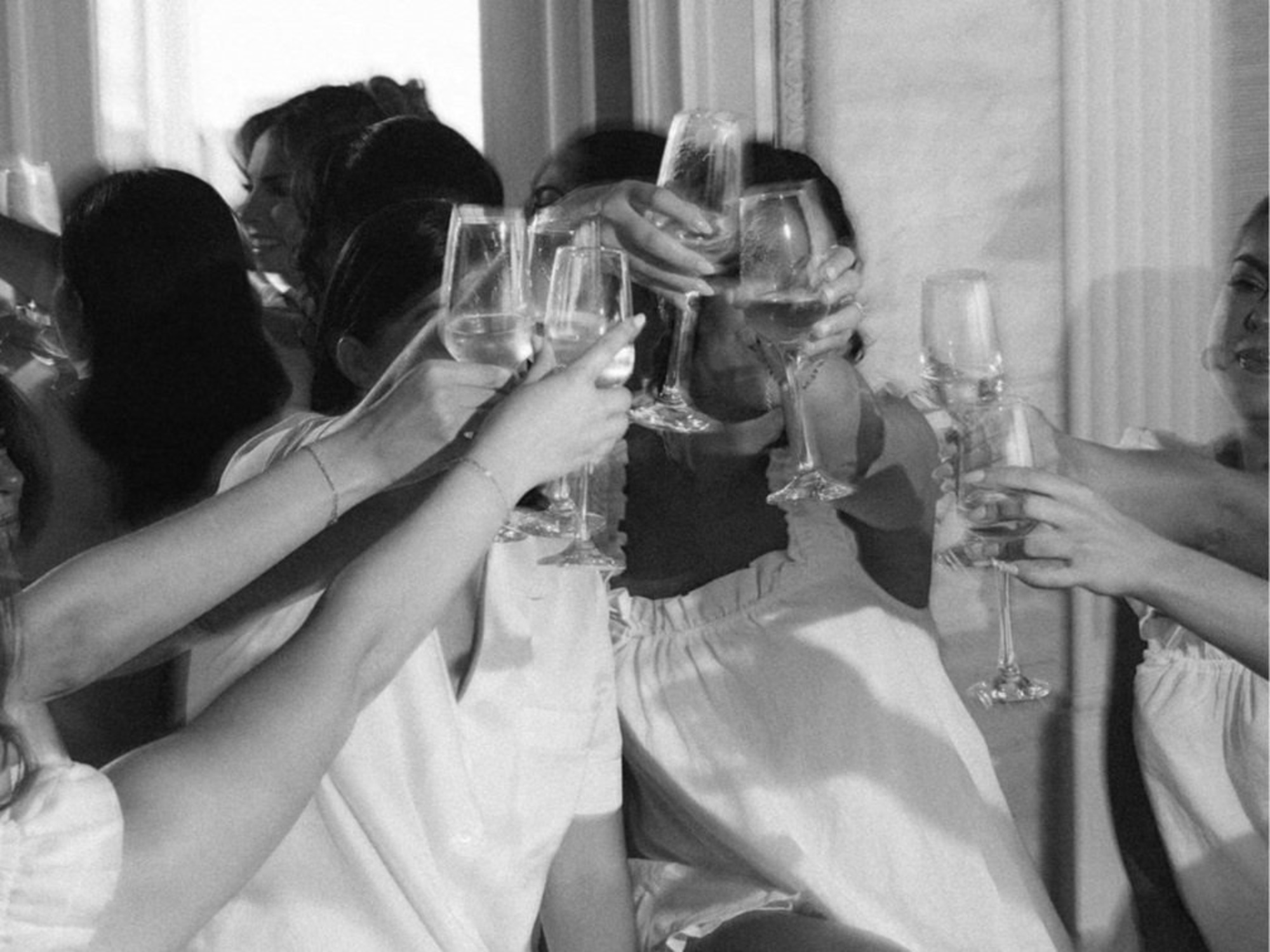 Bridal party raises champagne glasses in a joyful pre-wedding toast.