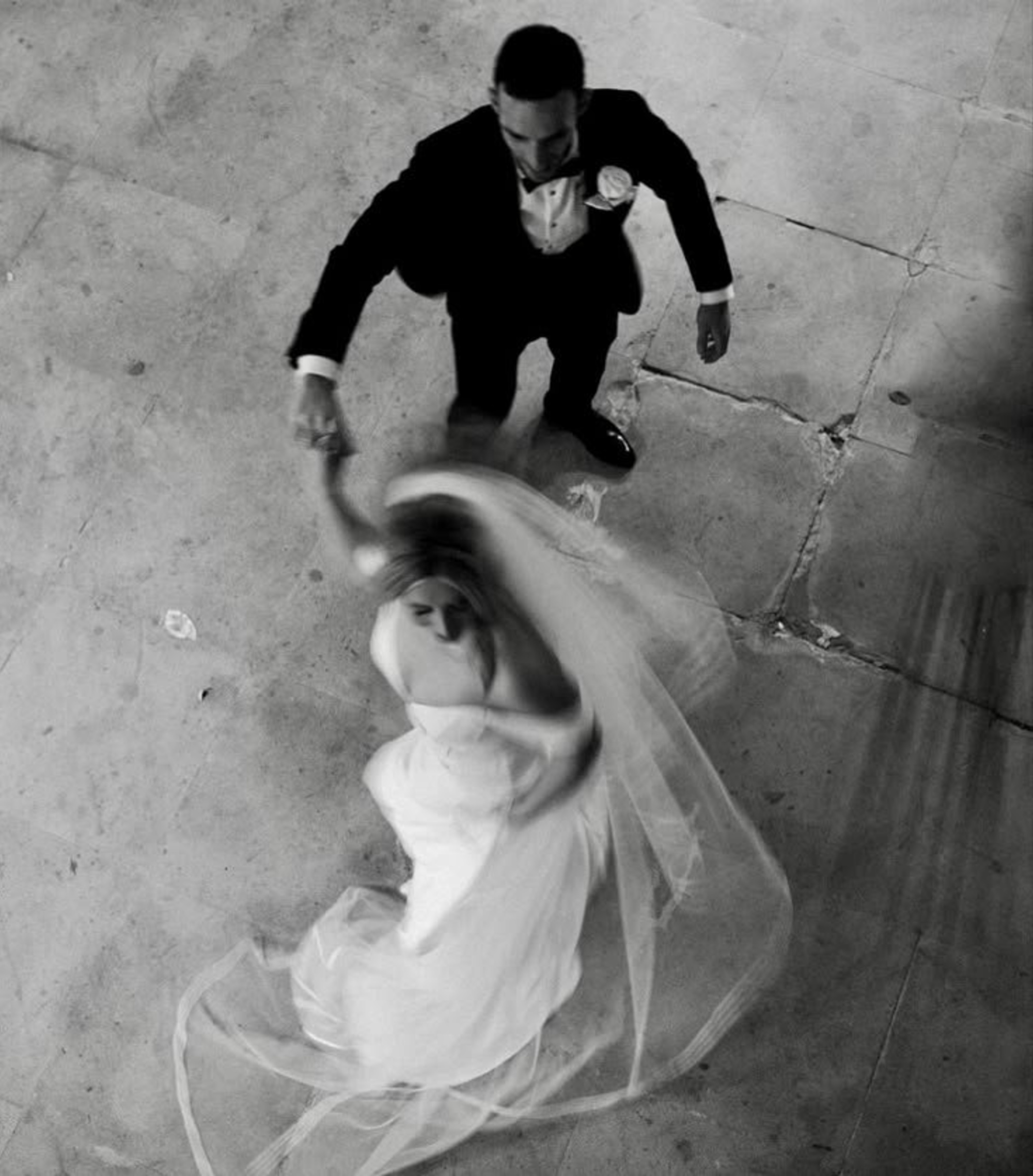 Black and white overhead photo of a bride and groom twirling during their wedding dance.