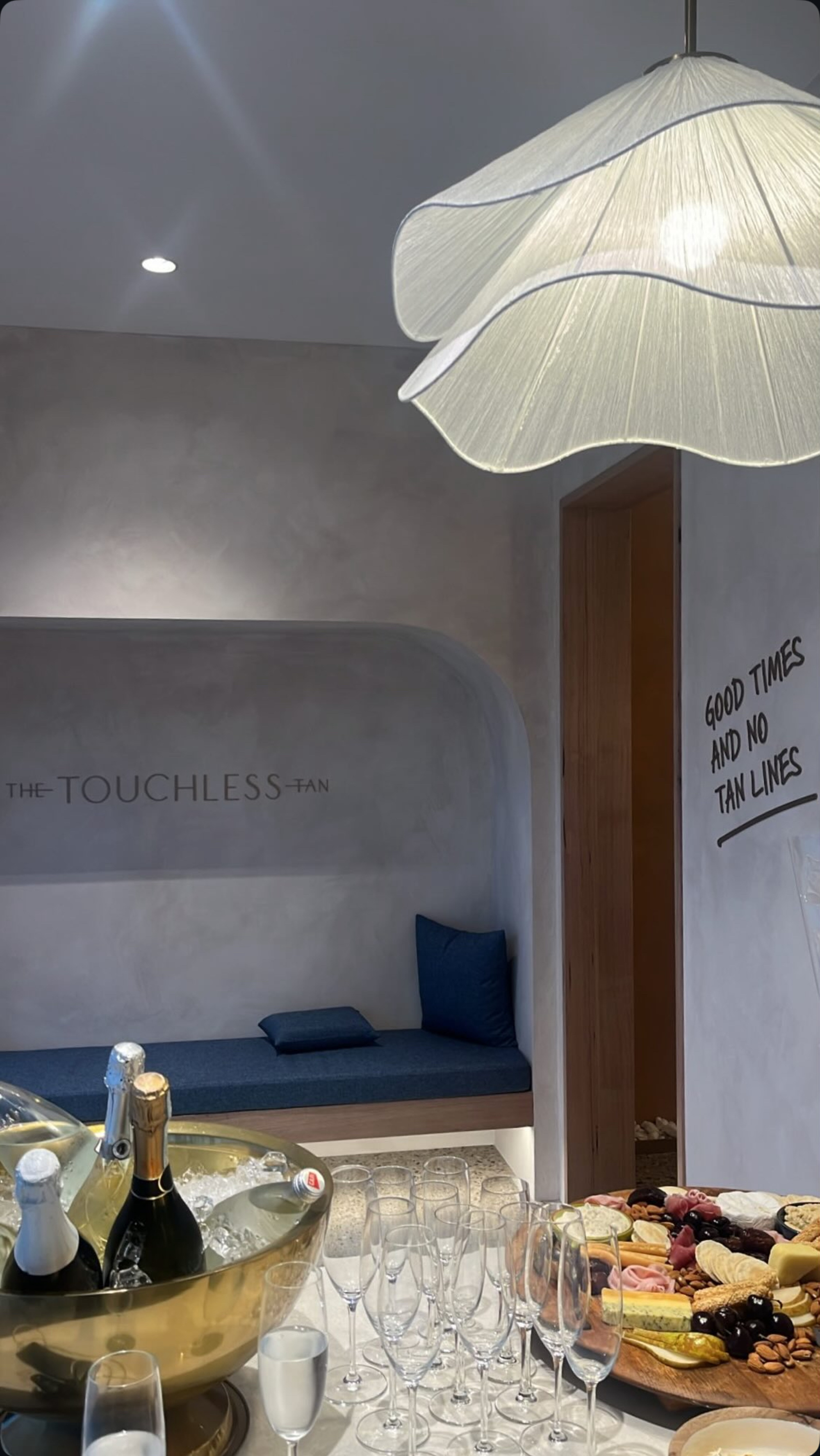Modern tanning studio lounge with champagne, glasses, and a charcuterie board set for a pre-wedding celebration.