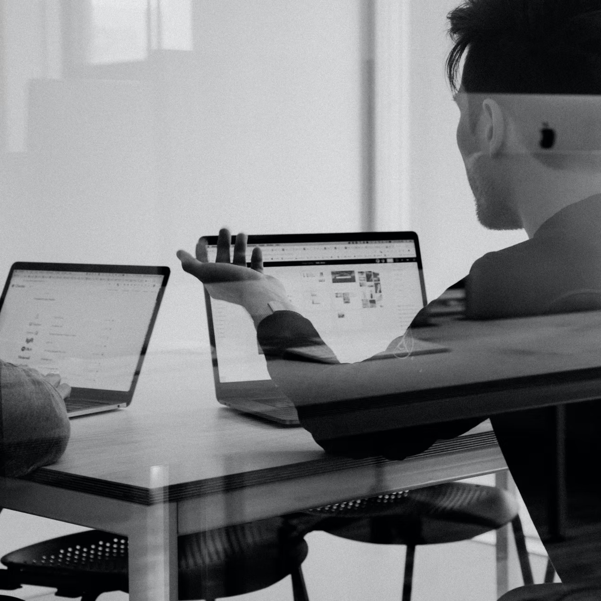 Two people collaborate on laptops during a wedding planning consultation in a modern office.