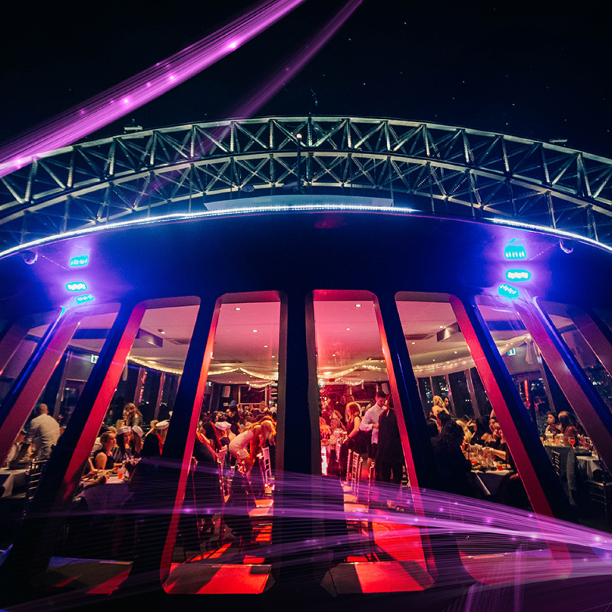 Nighttime wedding reception on a modern boat venue with colorful lights and guests dining inside